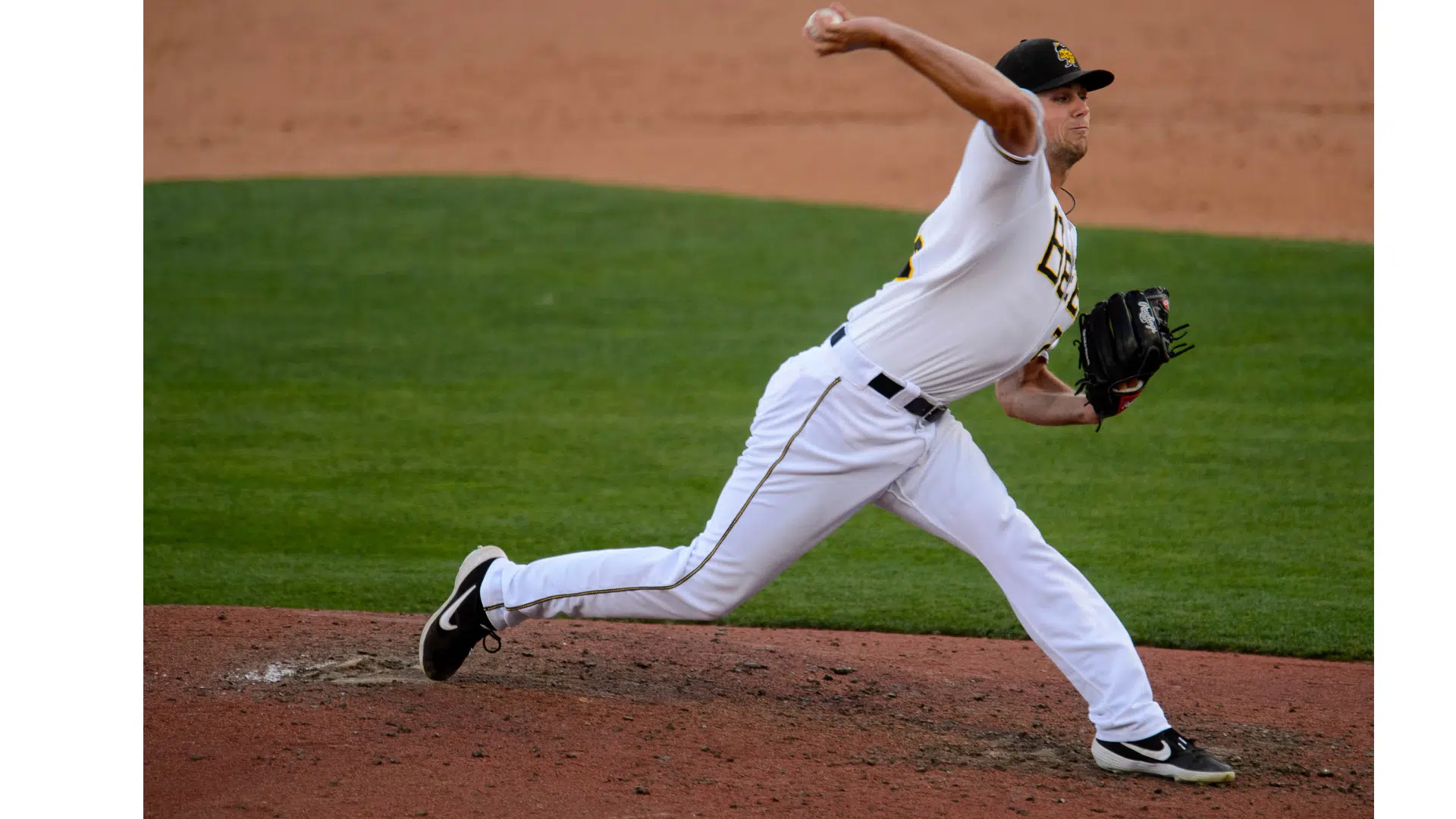 a baseball pitcher in a white uniform throwing a pitch from the mound during a game on a green field