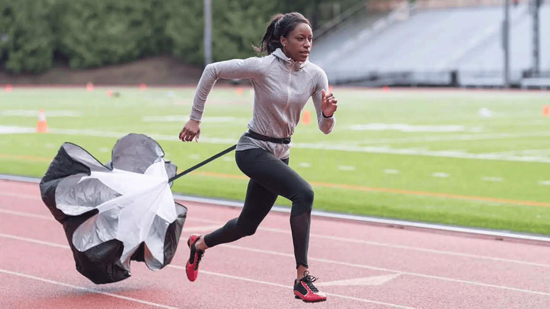 a female athlete sprinting on a track pulling a resistance parachute illustrating what is conditioning in sports training