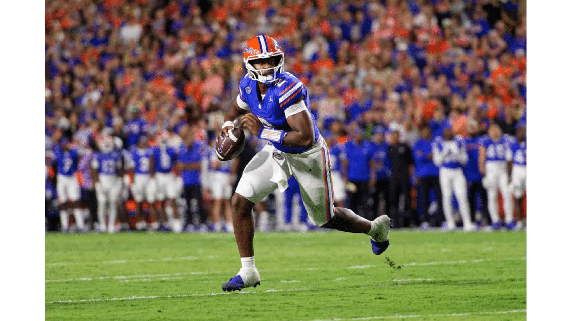 a florida gators football player in a blue jersey runs with the ball during a game with a crowded stadium in the background