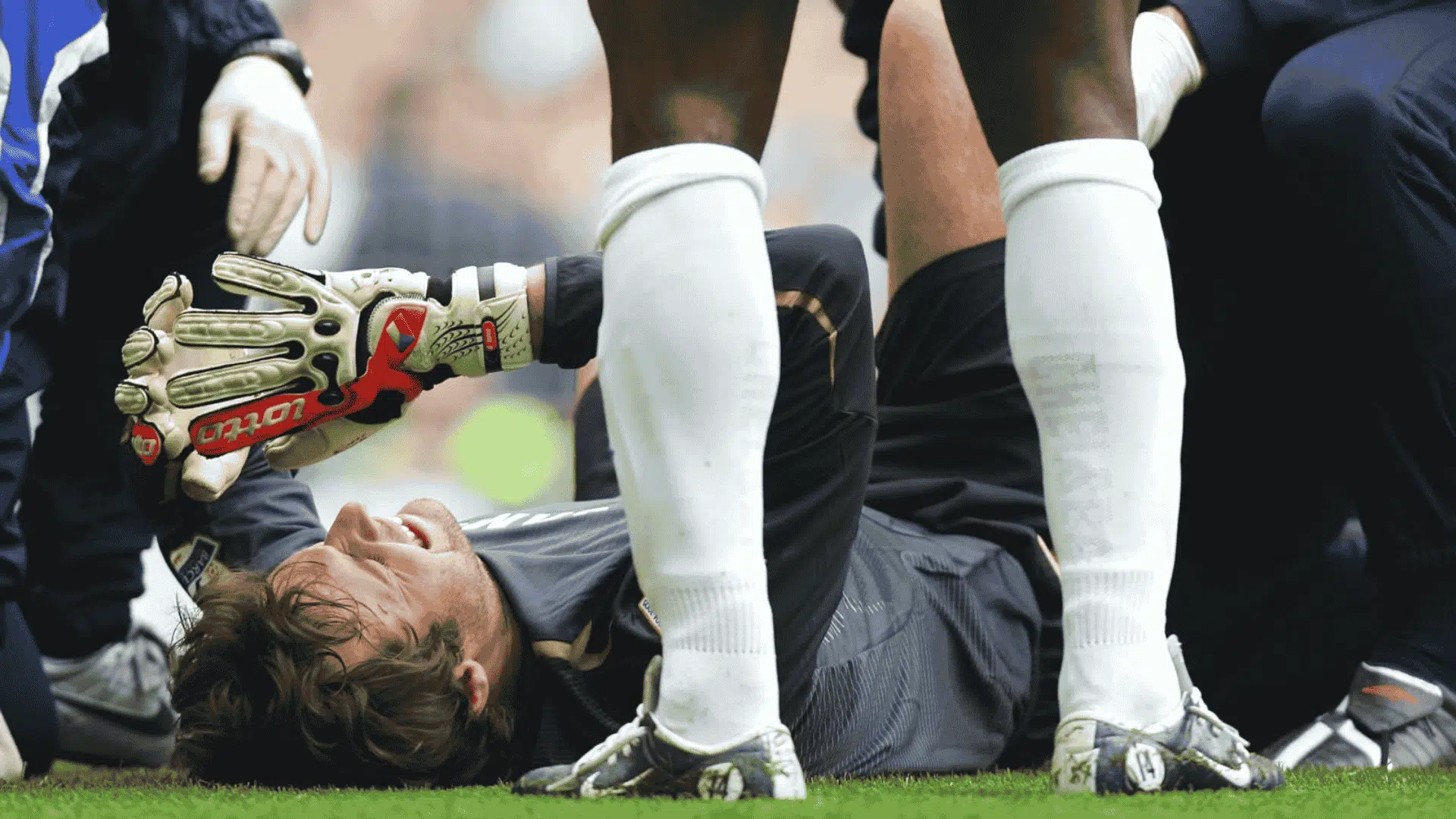 a football player lying on the field in pain as medical staff assist him showing one of the worst football injuries during a match