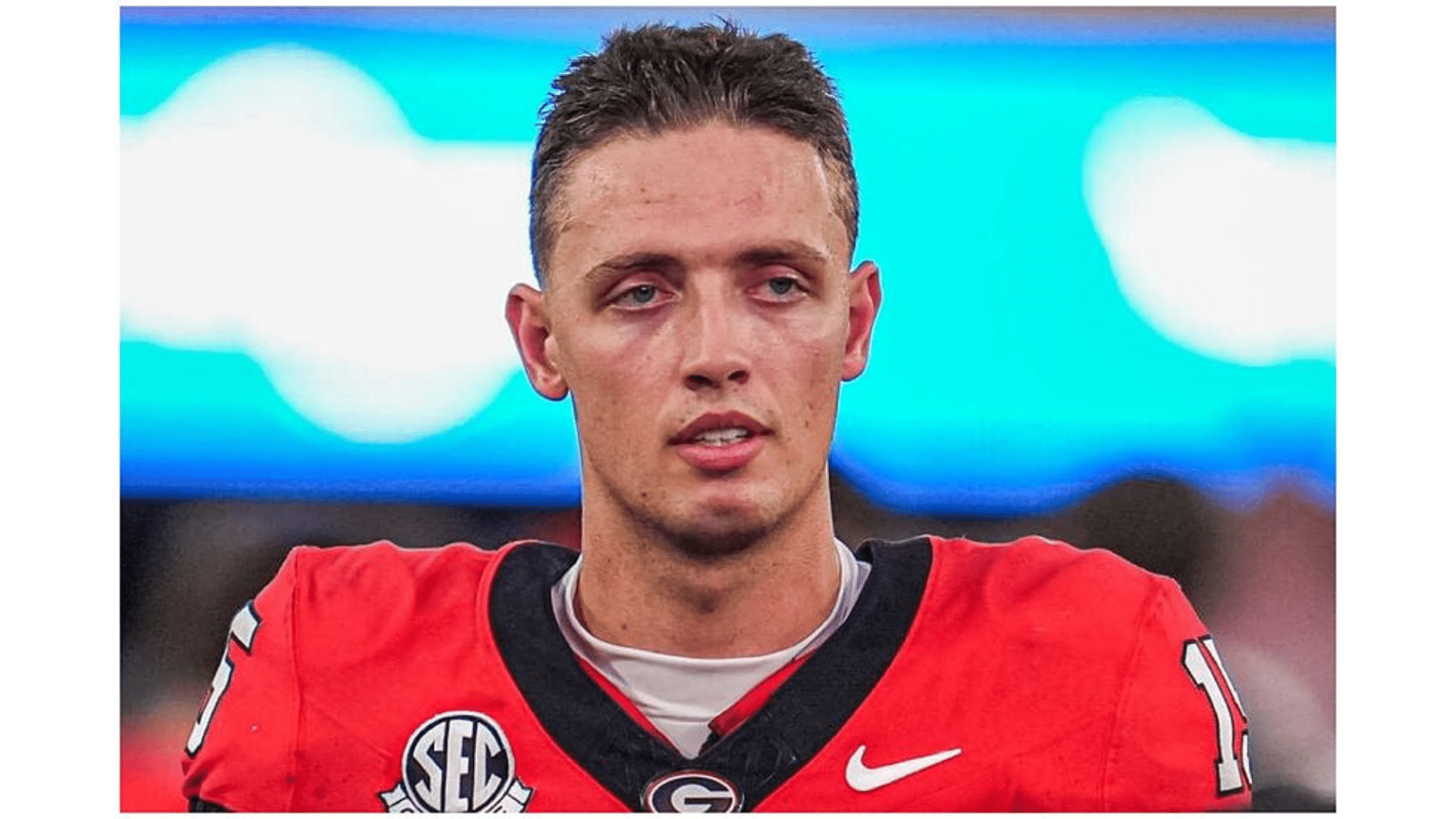 a football player wearing a red jersey with number 17 looks focused on the field during a game with a blurred stadium background