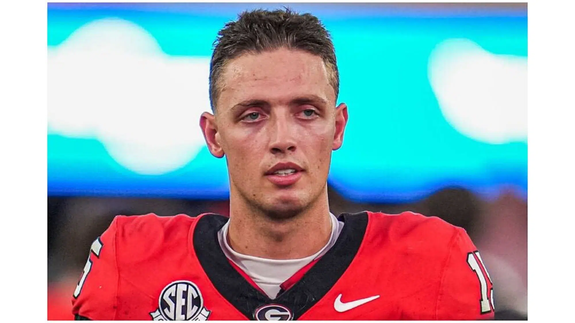 a football player wearing a red jersey with number 17 looks focused on the field during a game with a blurred stadium background