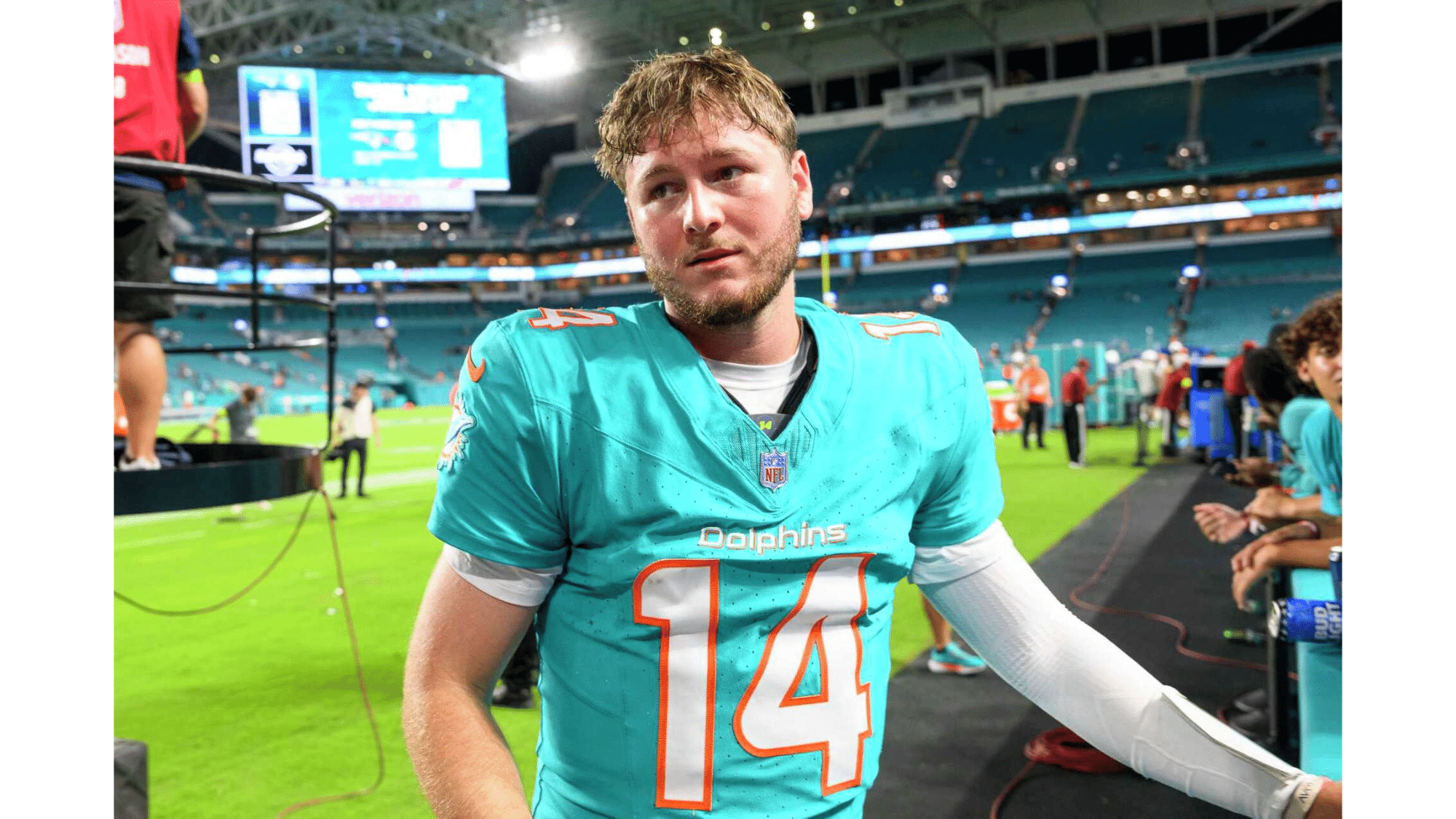 a miami dolphins football player highest nil deals wearing number 14 stands on the sideline after a game inside a large stadium
