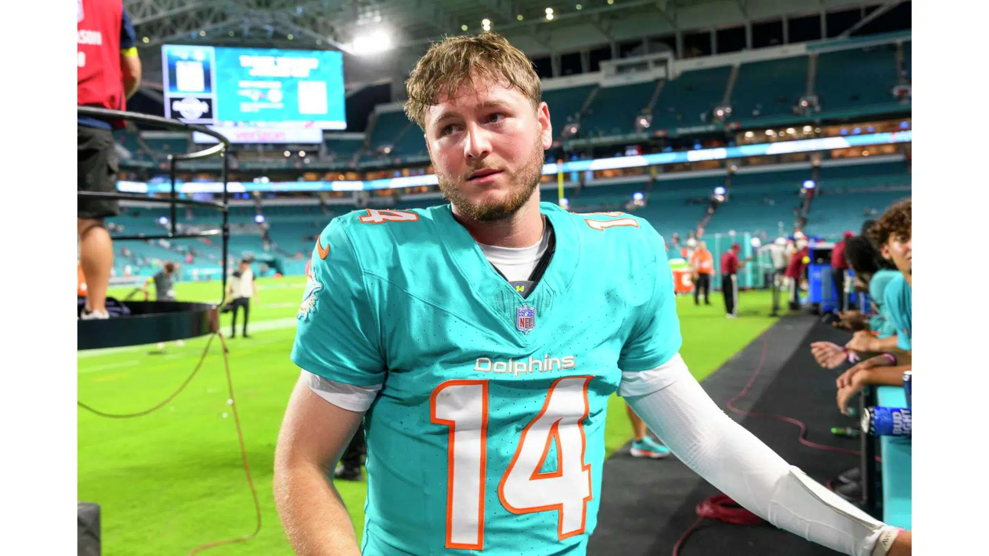 a miami dolphins football player highest nil deals wearing number 14 stands on the sideline after a game inside a large stadium