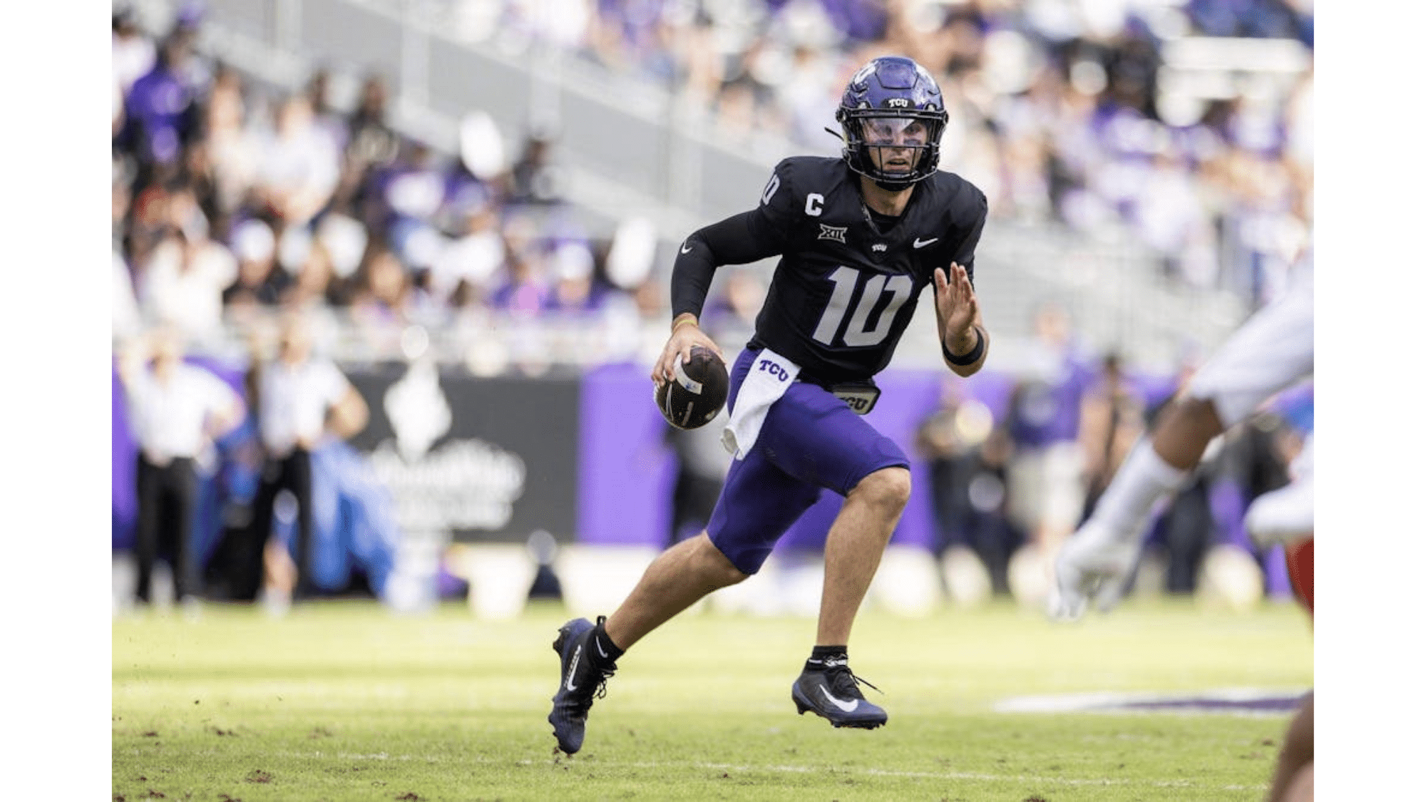 a tuc football top nil earners wearing number 10 runs with the ball during a game while a defender approaches on the field