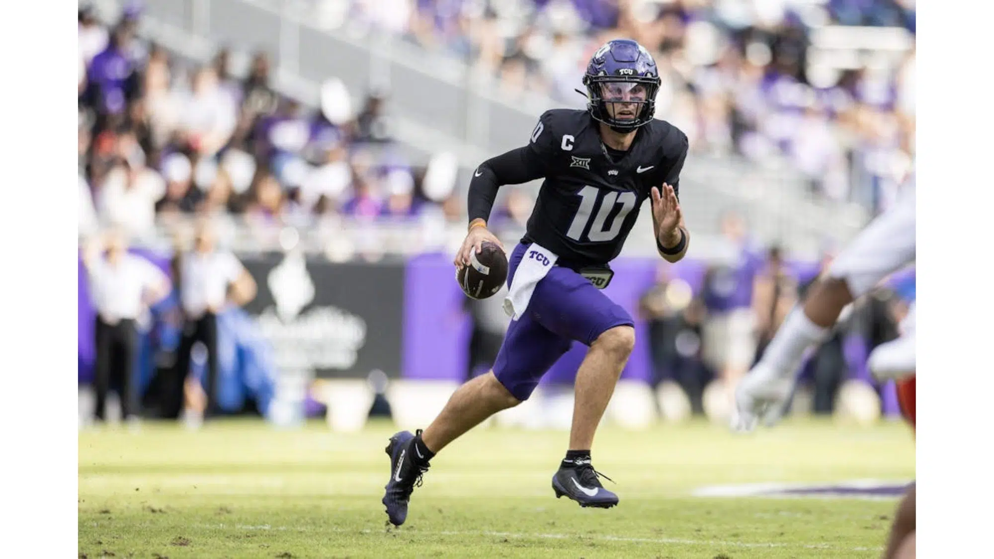 a tuc football top nil earners wearing number 10 runs with the ball during a game while a defender approaches on the field