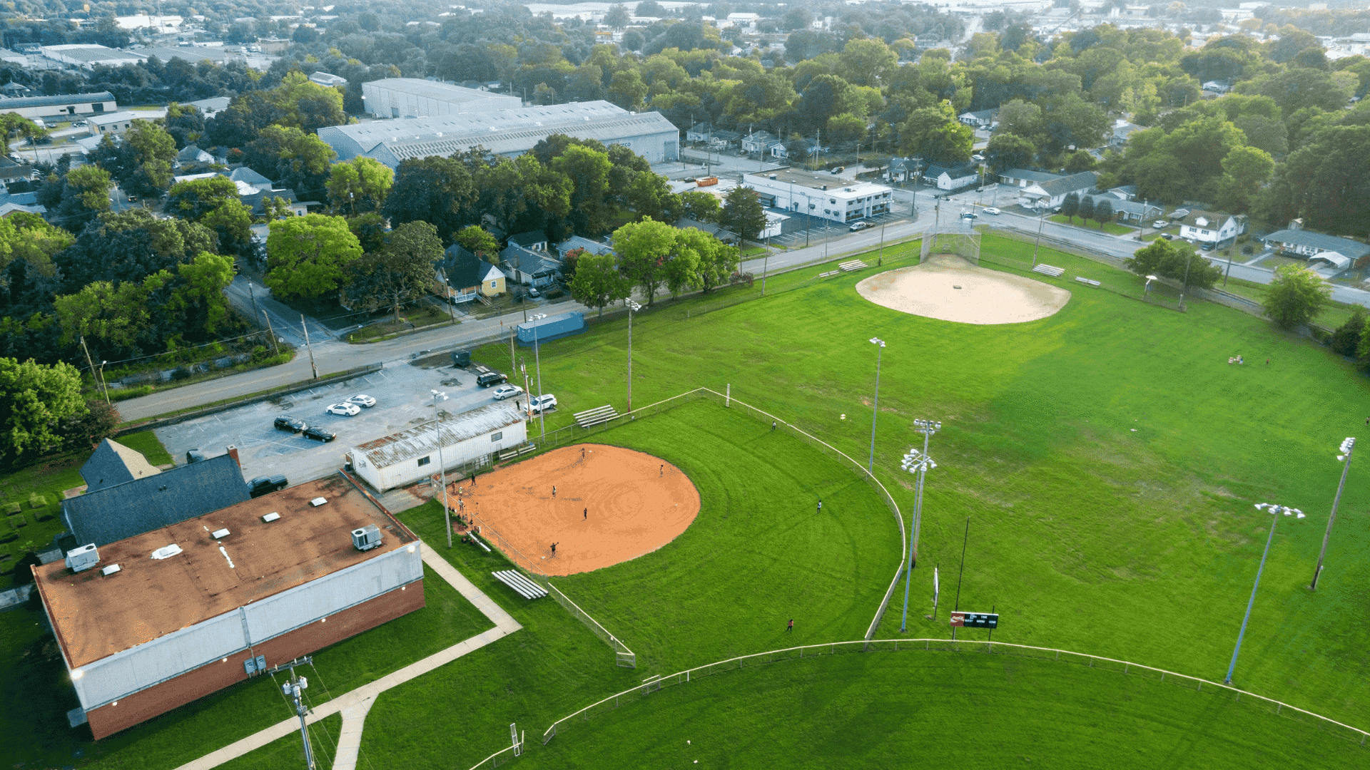 aerial view of two baseball fields beside a neighborhood and tree lined streets