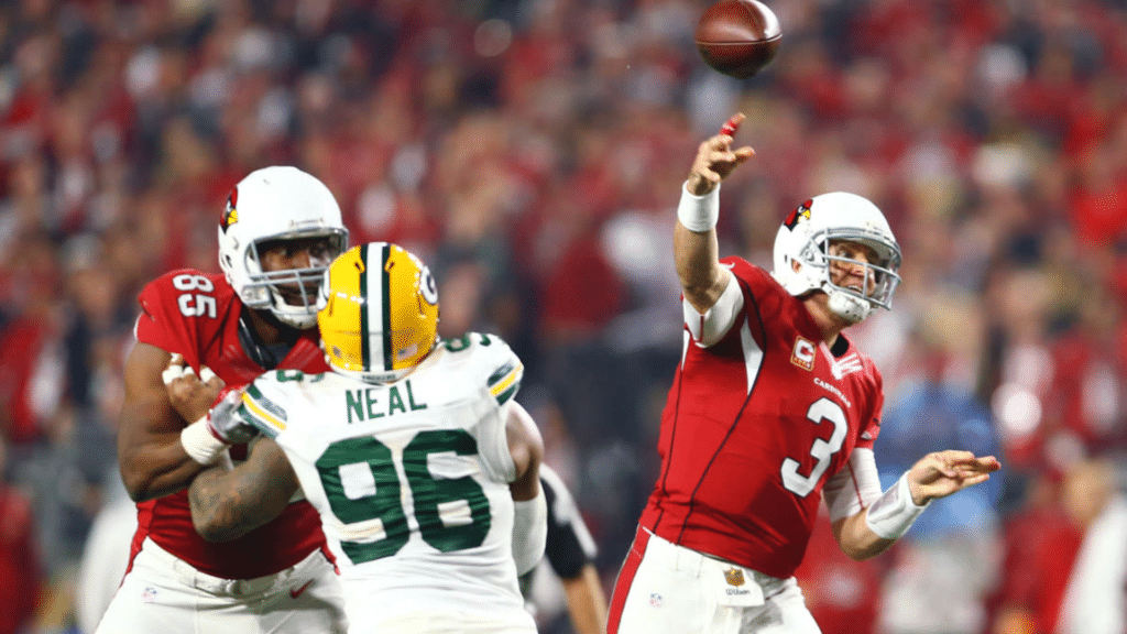 best qb of all time in red jersey throws a football during a game as defenders rush toward him
