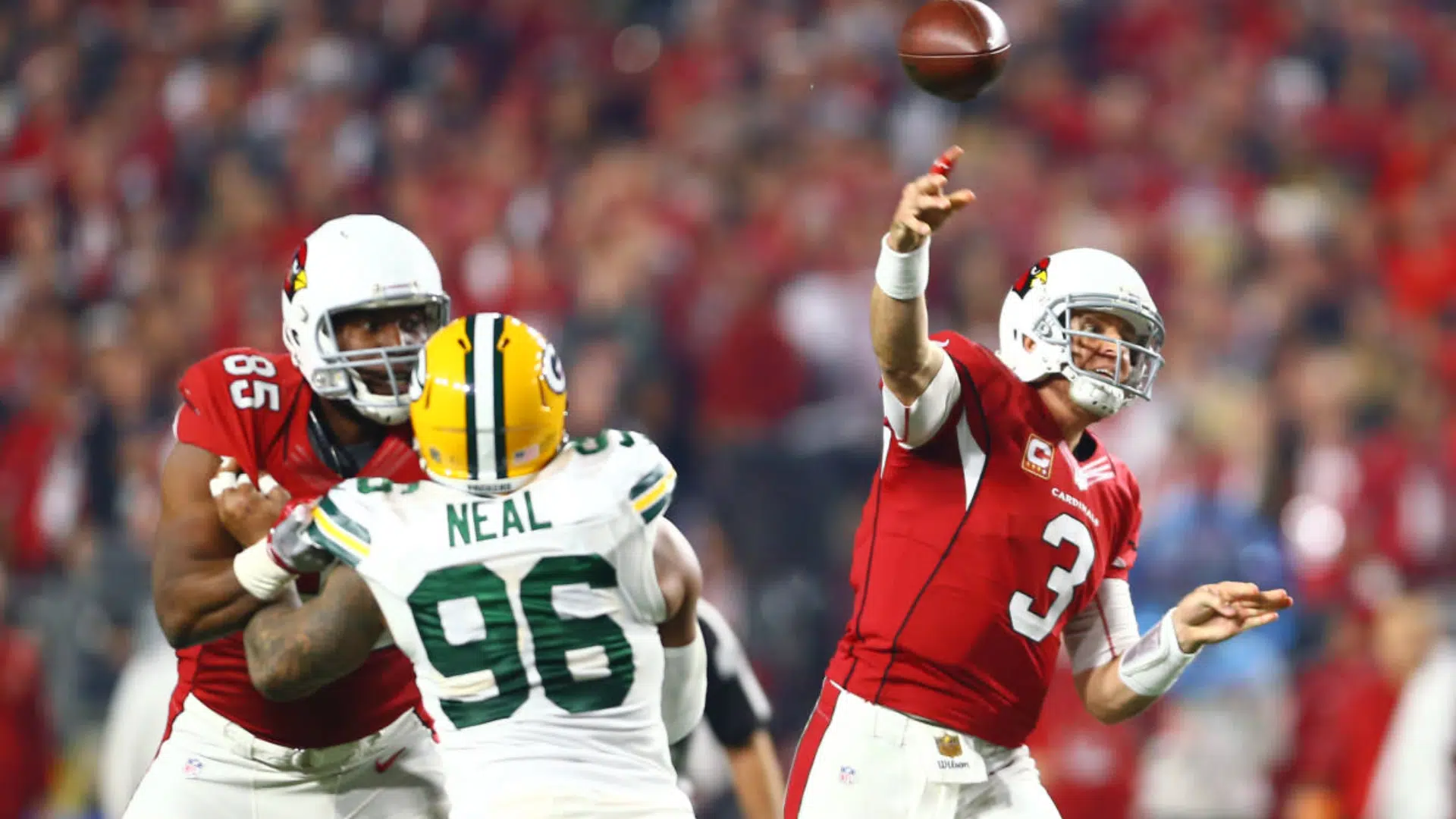 best qb of all time in red jersey throws a football during a game as defenders rush toward him