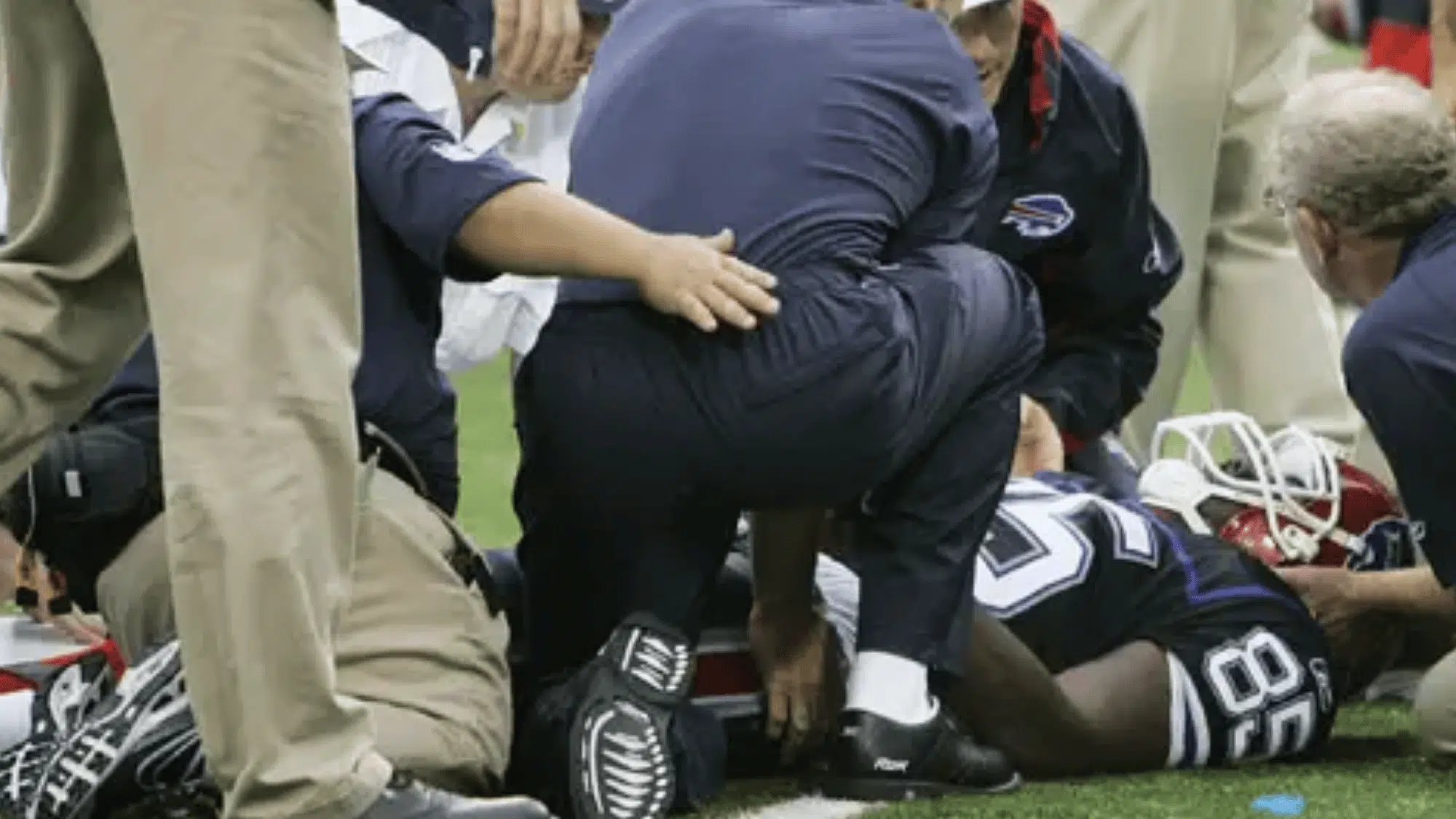 buffalo bills player kevin everett lying on the field as medical staff kneel to assist him