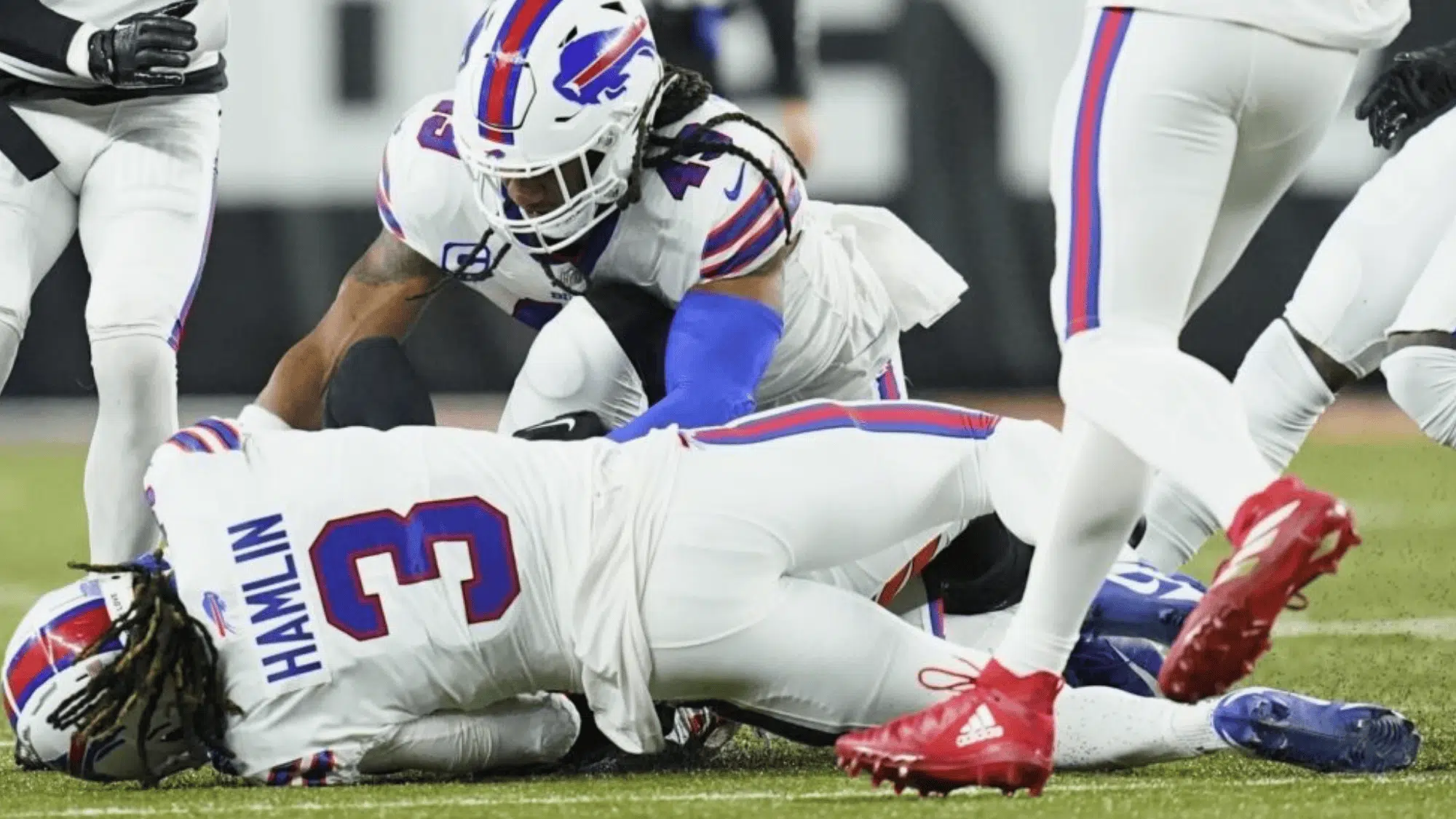 buffalo bills players damar hamlin kneel beside a teammate lying on the field after a play