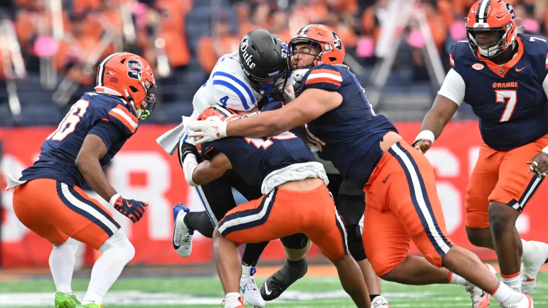 football players making a strong tackle defense