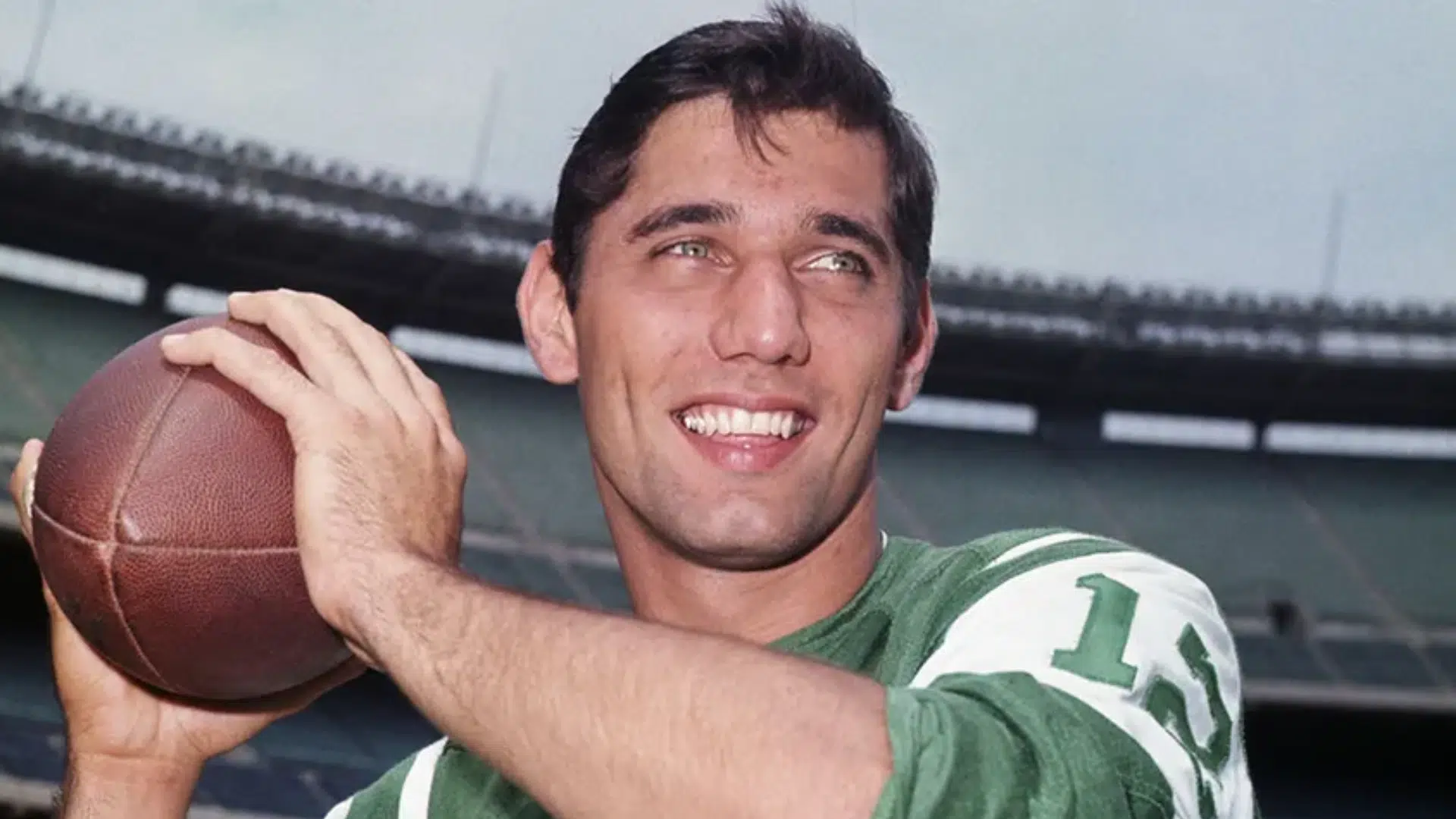 joe namathclassic era smiles while holding a football on the field