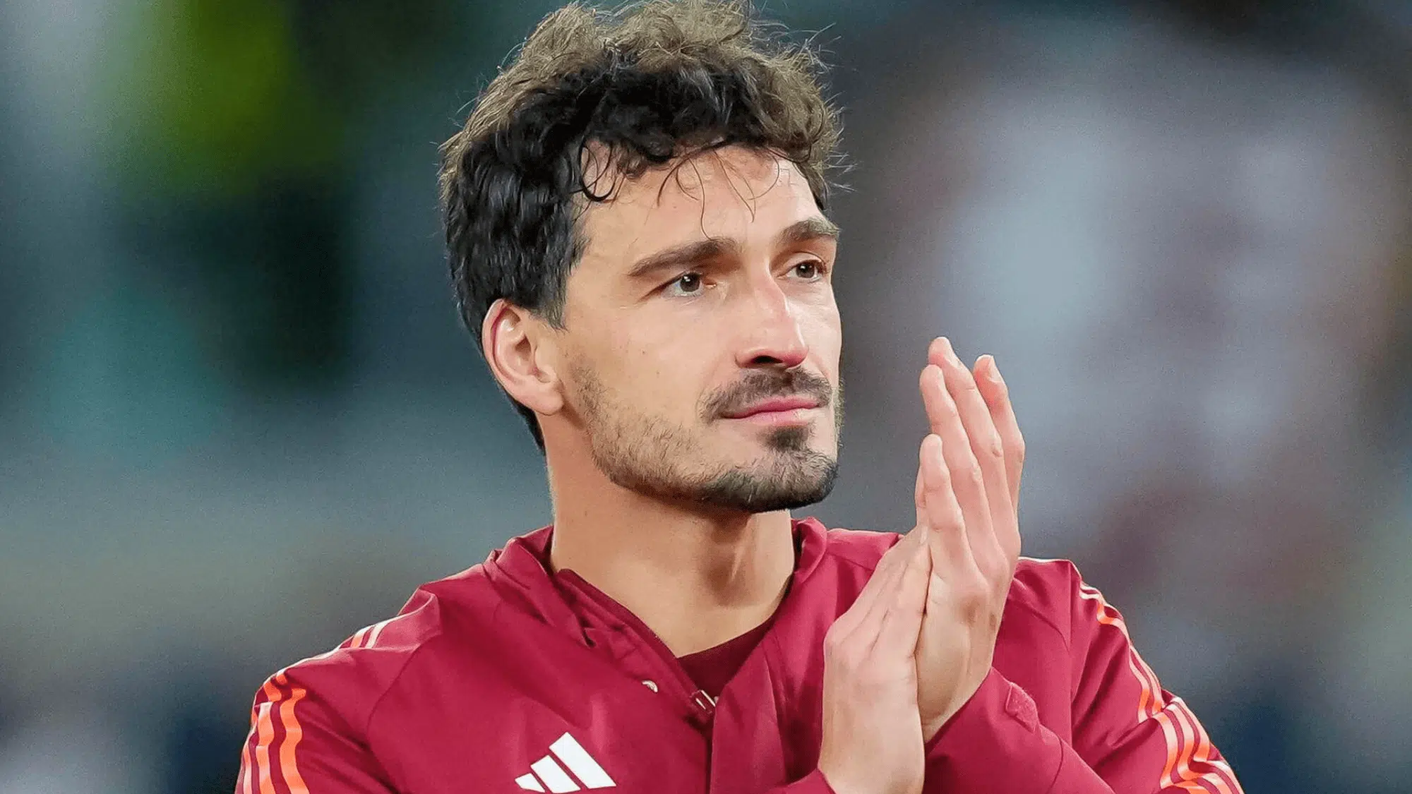 mats hummels in a red jersey applauding on the field