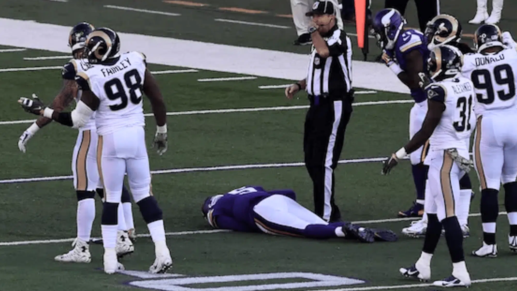 minnesota vikings player teddy bridgewater lying on the field surrounded by rams players and a referee