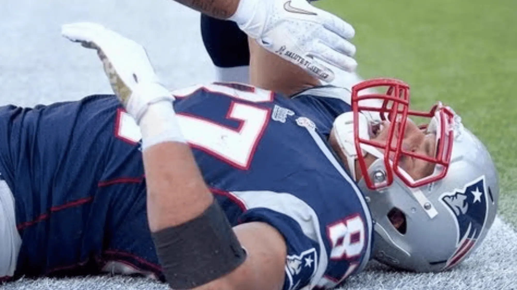 new england patriots quarterback rob gronkowski lying on the turf clutching his chest after a hit