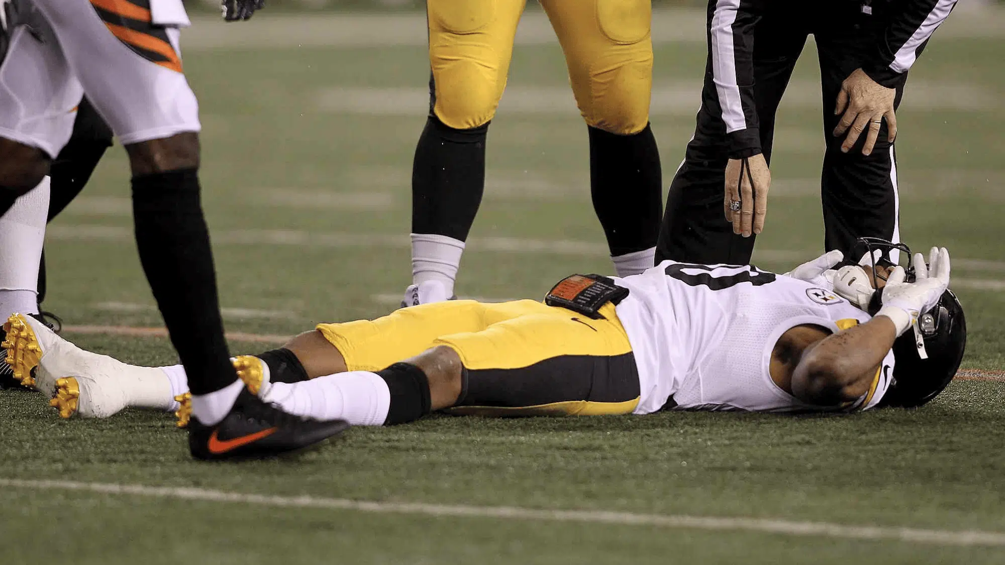 pittsburgh steelers player ryan shazier lying flat on the field as a referee checks on him