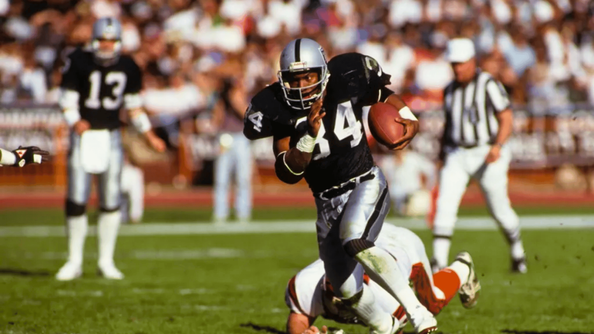 raiders player bo jackson running back wearing number 34 carries the football while a defender falls behind him