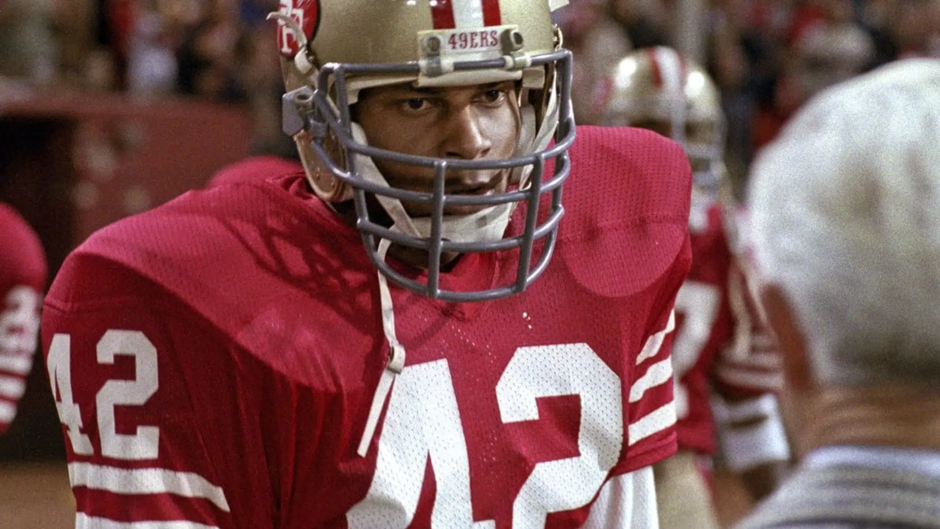 ronnie lott a defensive back player in a red jersey focused before play