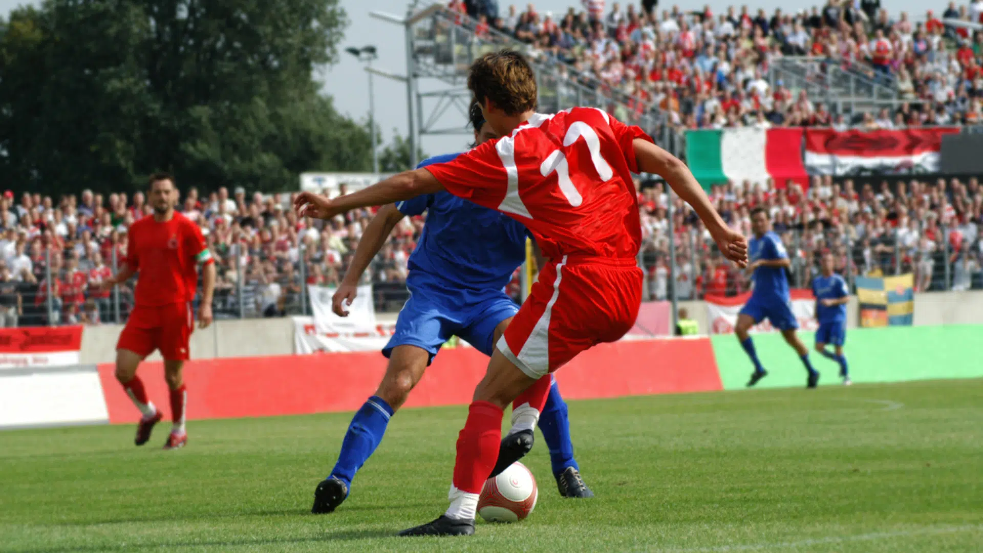 soccer players compete for the ball on a grass field before a packed crowd with a banner reading what does cdm mean in soccer