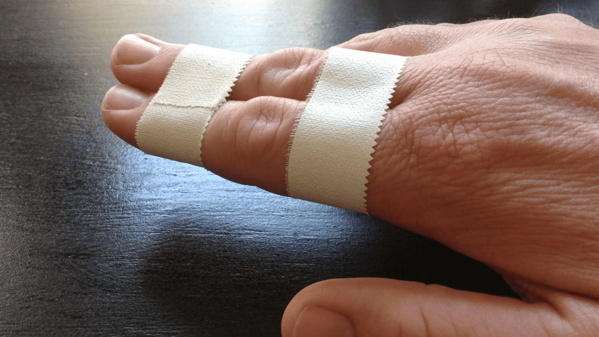 this image shows a hand with two fingers wrapped in white tape, likely for support or injury protection.