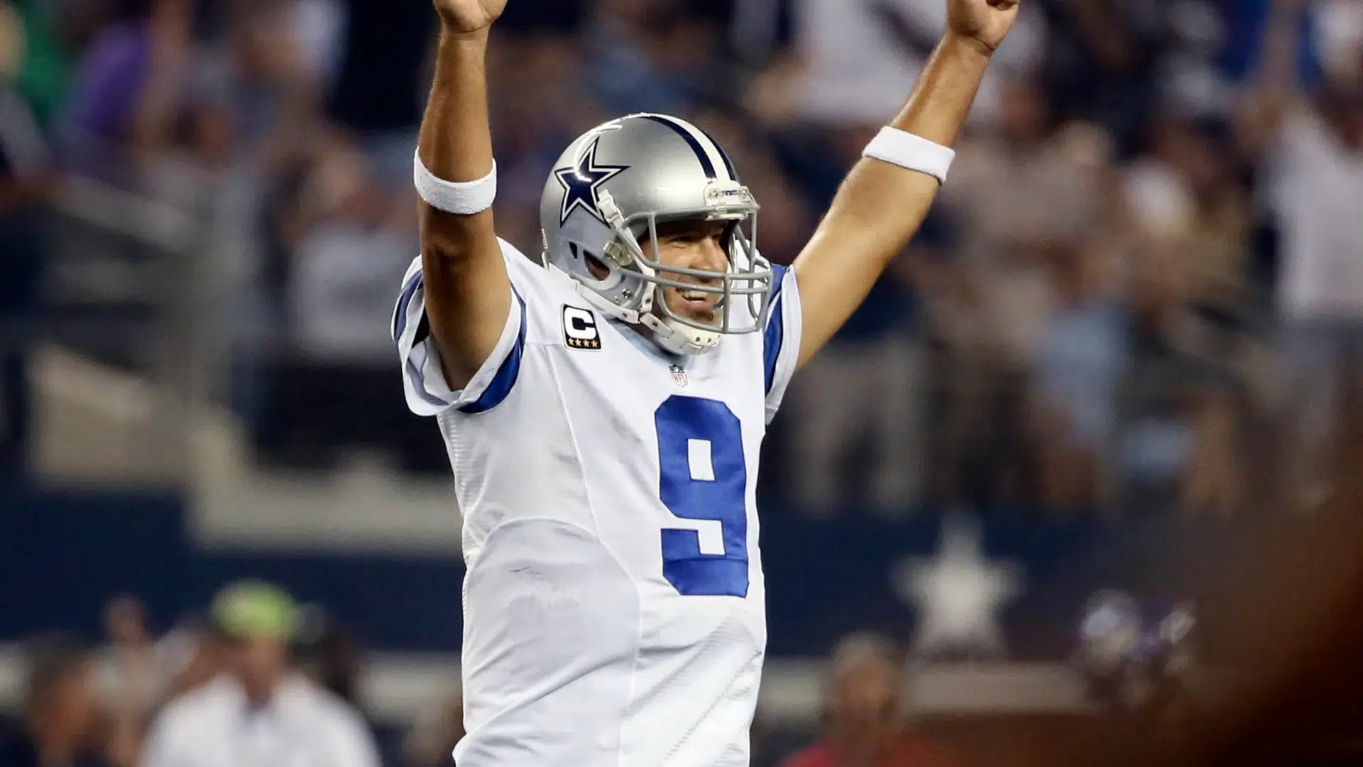 tony romo raises both arms in celebration after a big play
