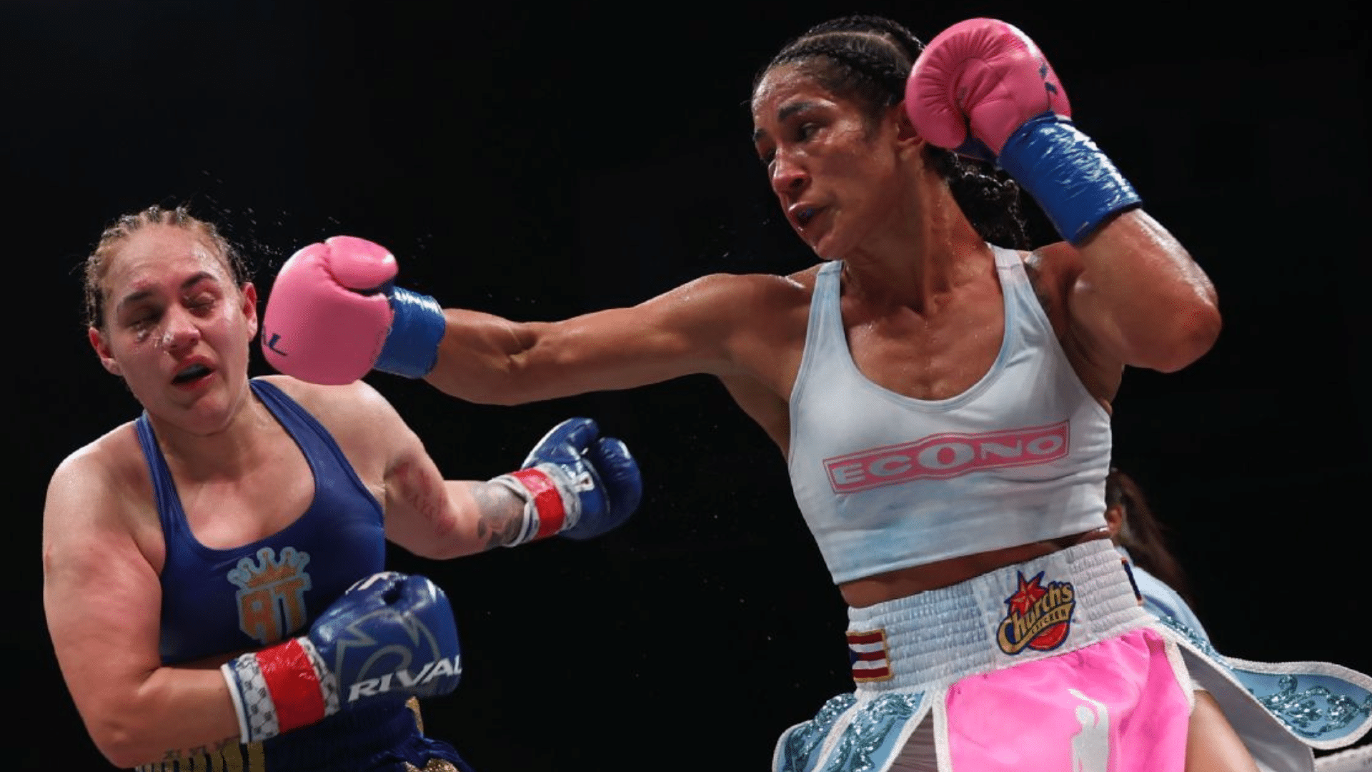 two female boxers are exchanging punches as one lands a clean right hook while the opponent absorbs the shot 