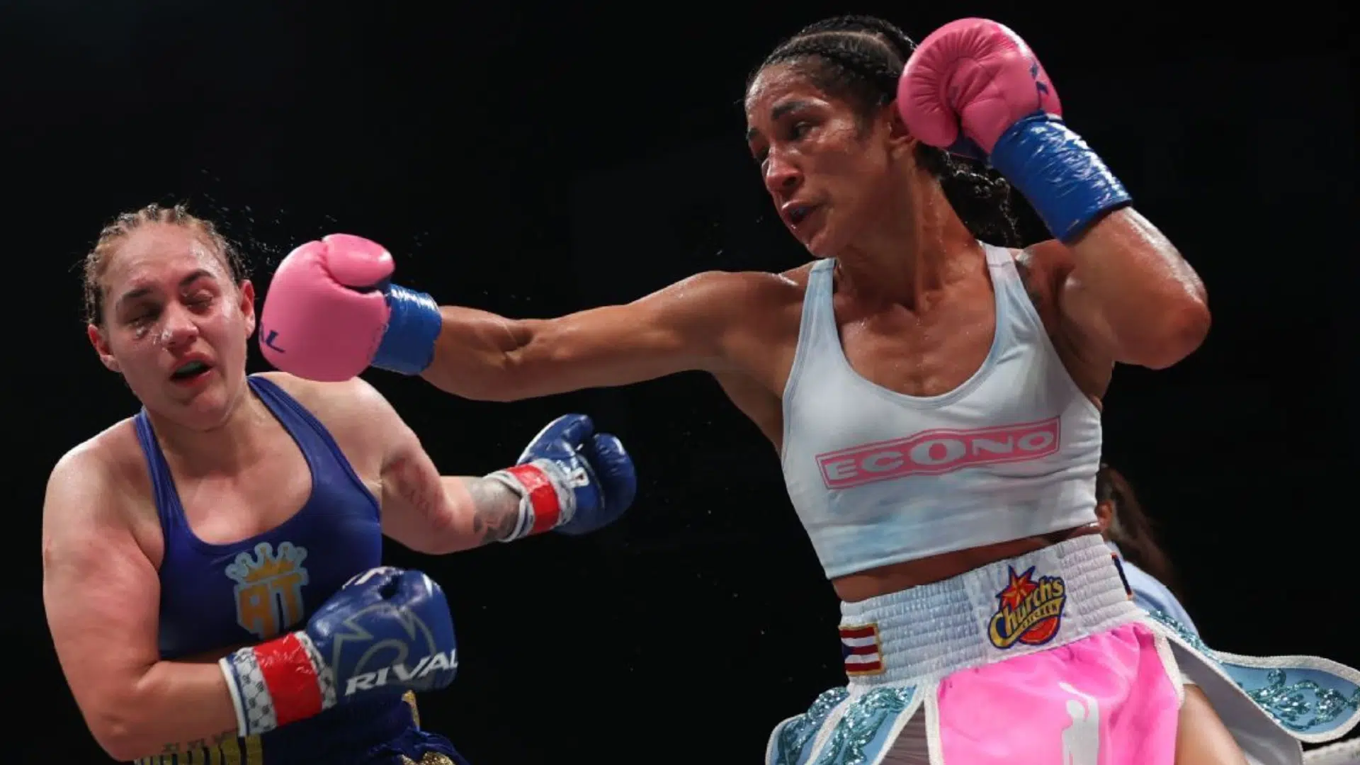 two female boxers are exchanging punches as one lands a clean right hook while the opponent absorbs the shot 