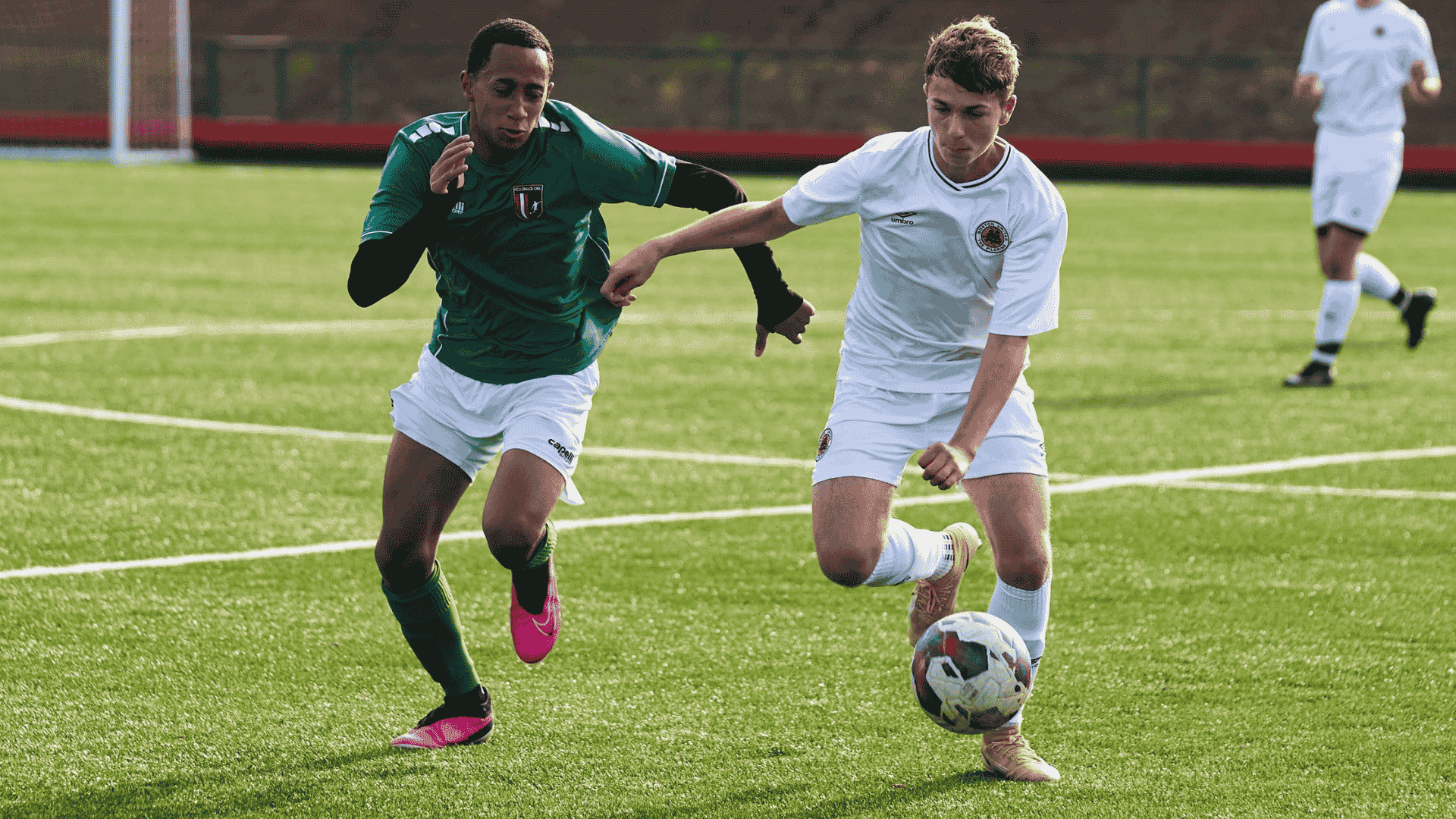 two football players run side by side chasing the football in an intense match