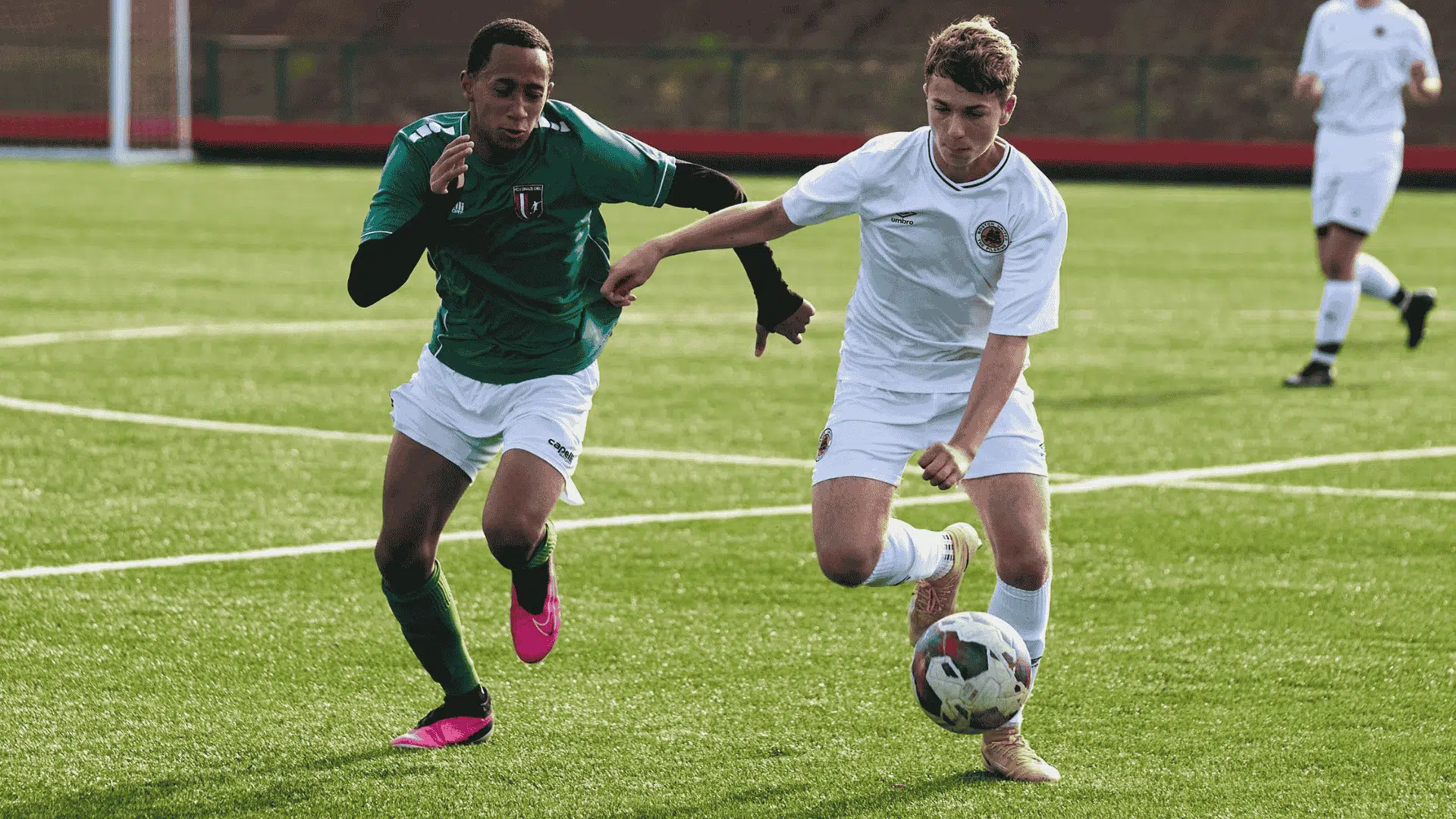 two football players run side by side chasing the football in an intense match