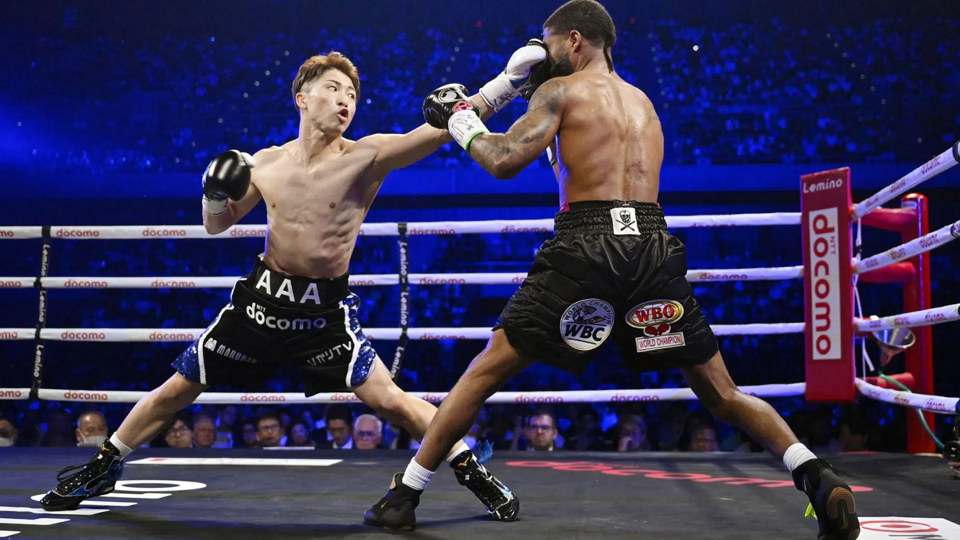 two professional boxers exchange punches inside a brightly lit ring