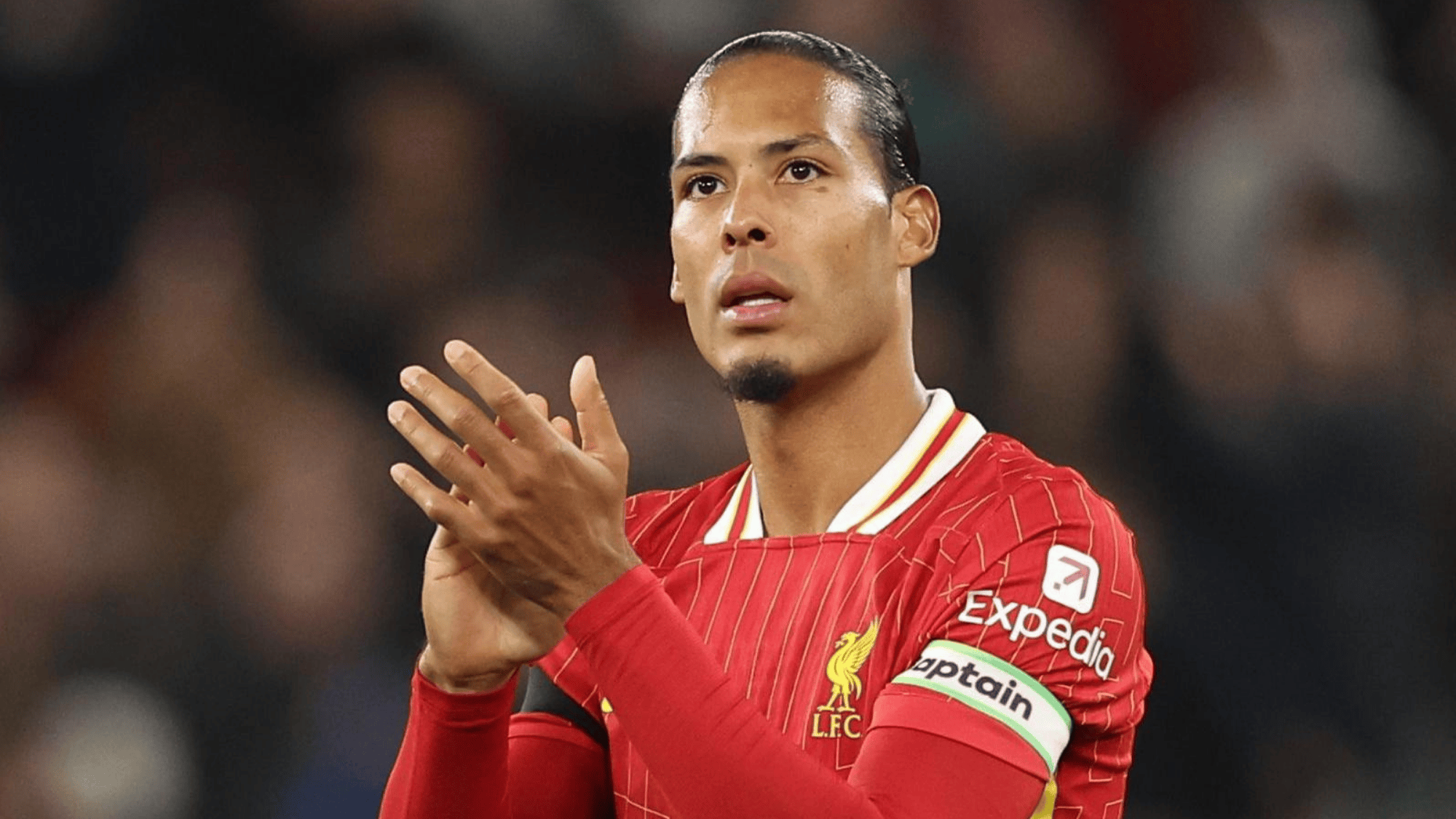 virgil van dijk in a red liverpool jersey clapping on the field
