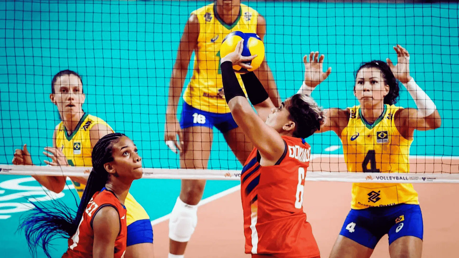 volleyball player in red team jumps to set the ball as defenders in other team prepare to block at the net