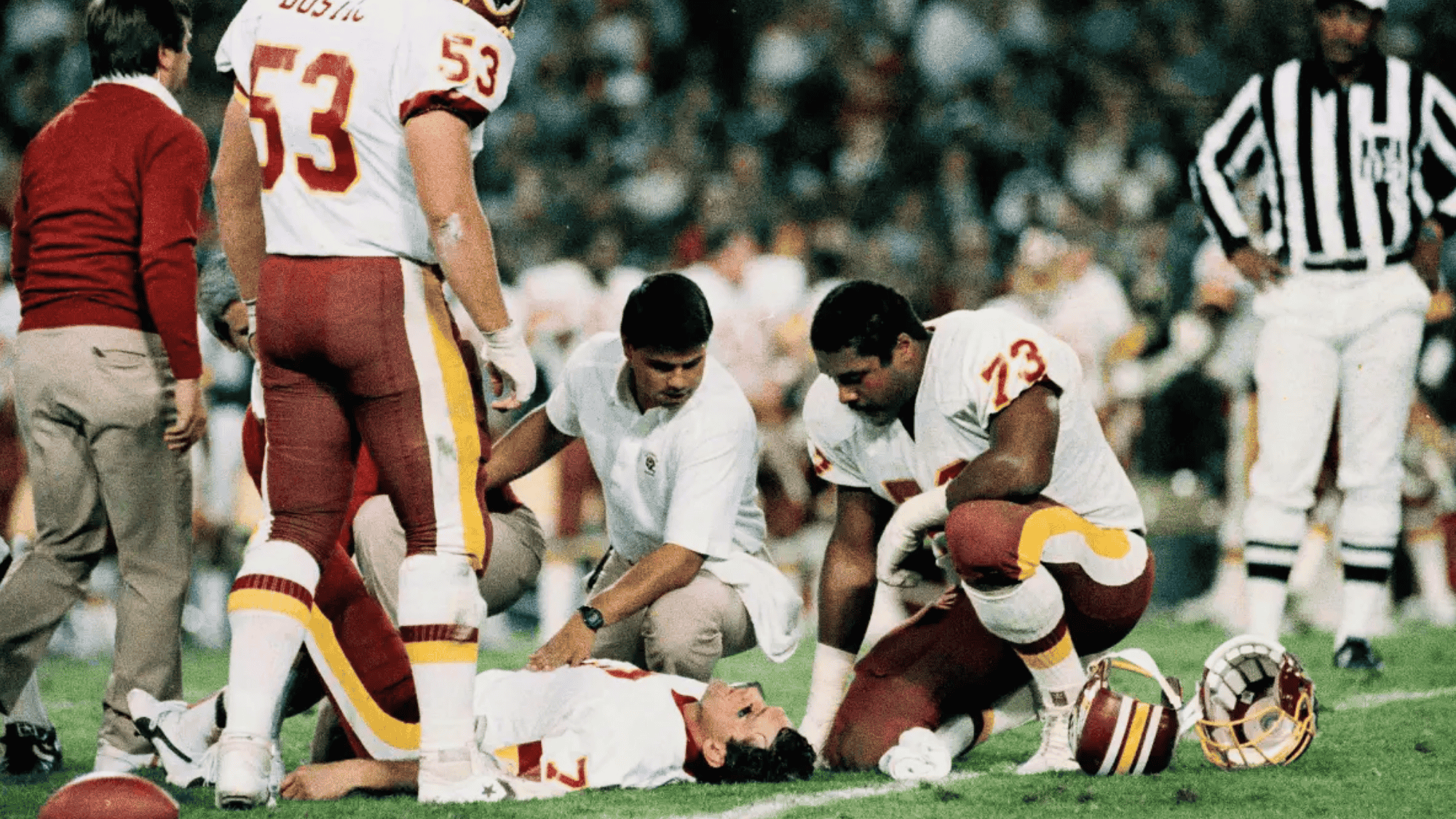 washington player joe theismann lying on the field as teammates and staff check on him