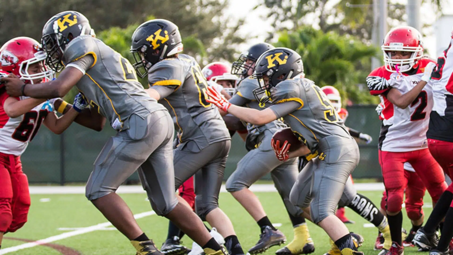youth american football players blocking and running during a game play on a field