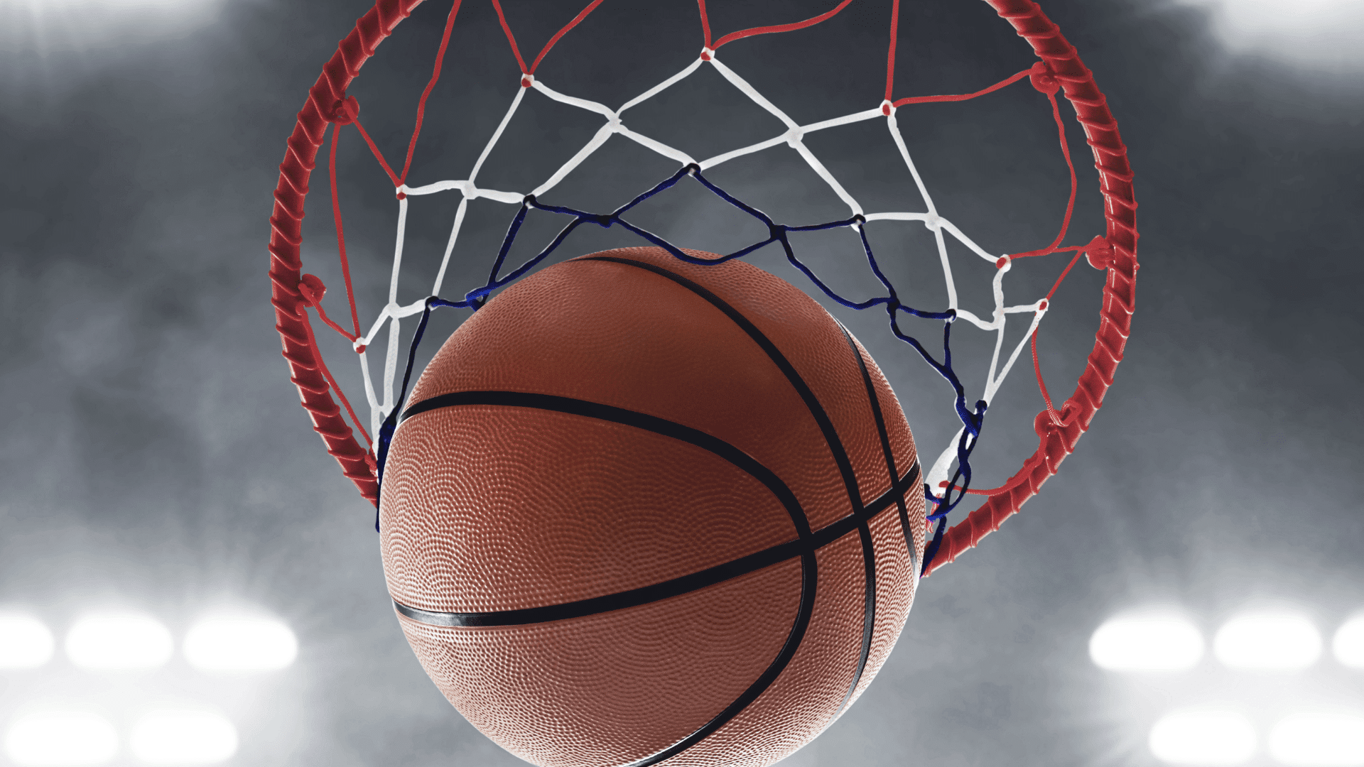 basketball going through the hoop with net and rim in focus under bright arena lights symbolizing a made three-point shot