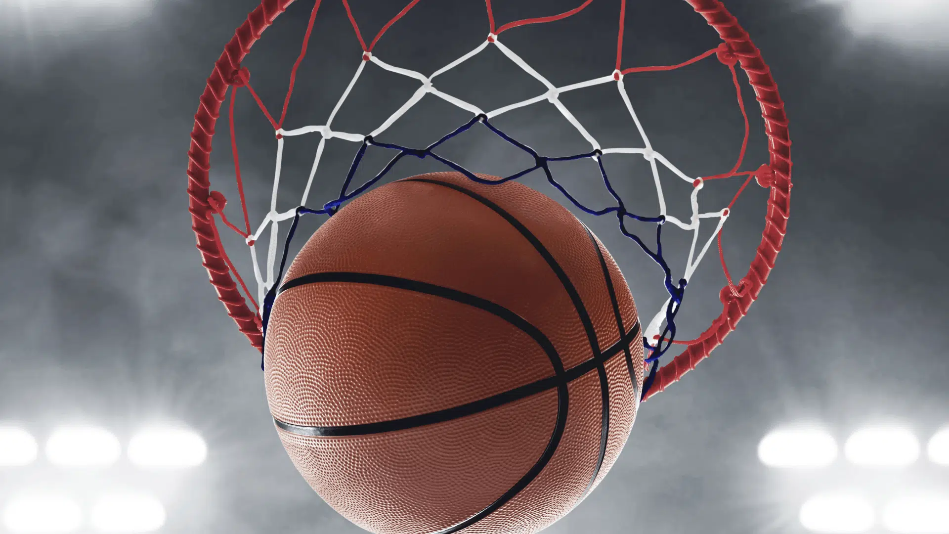 basketball going through the hoop with net and rim in focus under bright arena lights symbolizing a made three-point shot