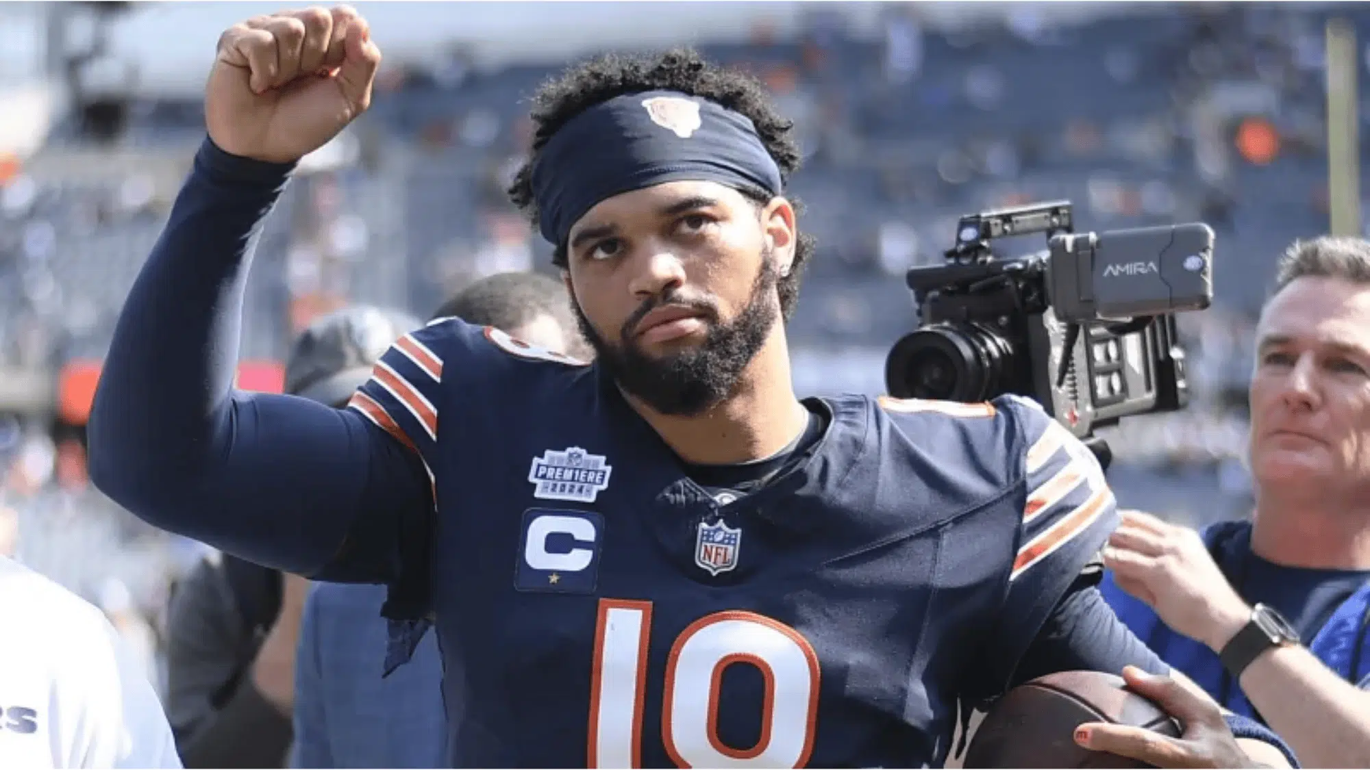 caleb williams in a navy blue jersey with the number 10 raises his fist confidently