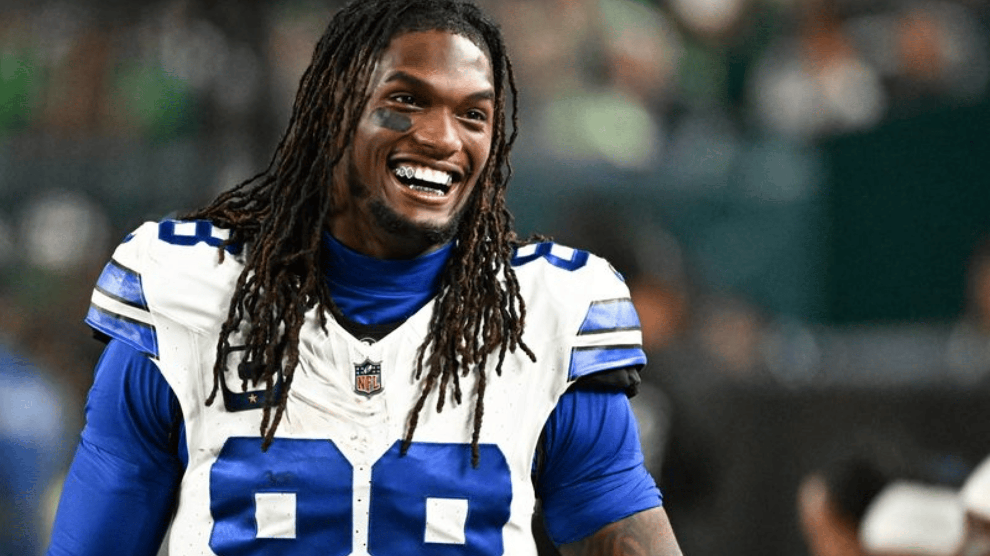 ceedee lamb wearing a white and blue uniform with number 88 standing on a blurred stadium background