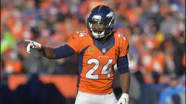 champ bailey in an orange denver broncos jersey, number 24, points while standing on the field