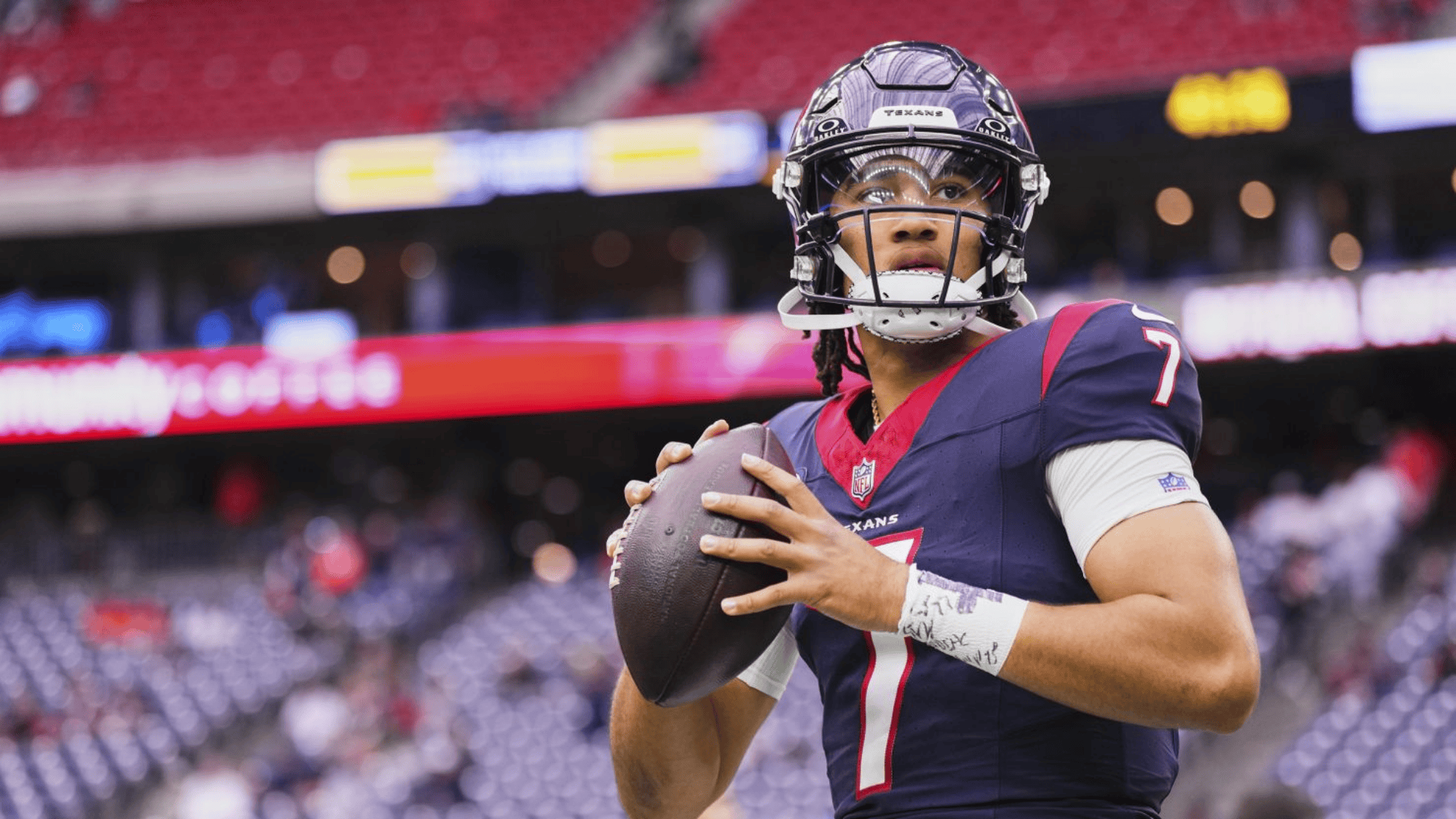 cj stroud in a navy and red uniform, number 7, prepares to throw a pass in a stadium