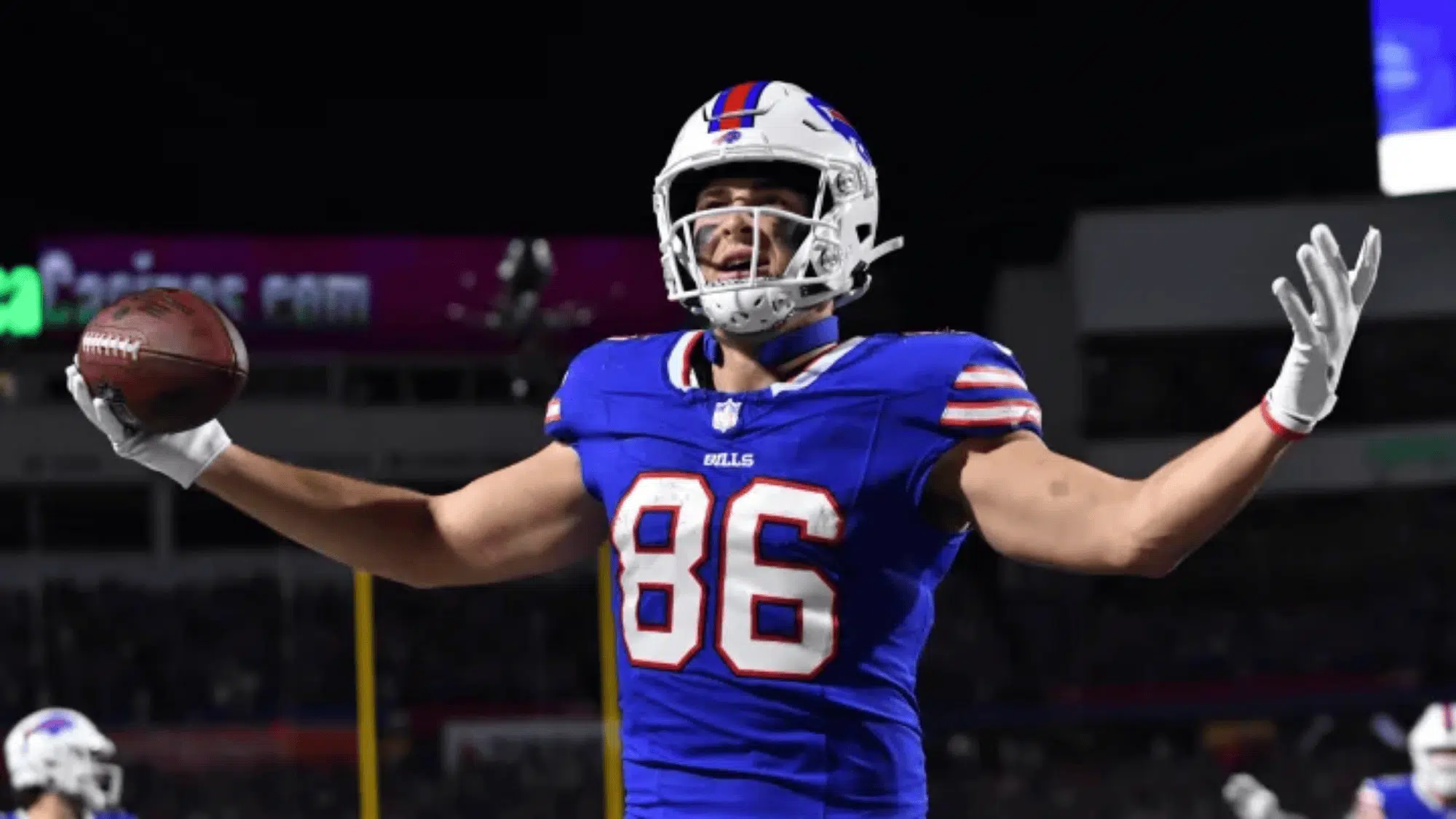 dalton kincaid in blue uniform and helmet number 86 celebrates with arms outstretched on a lit stadium field at night expressing triumph