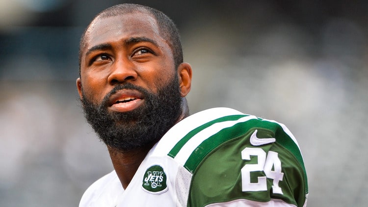 darrelle revis in a green and white jersey, number 24, looks upward with a thoughtful expression