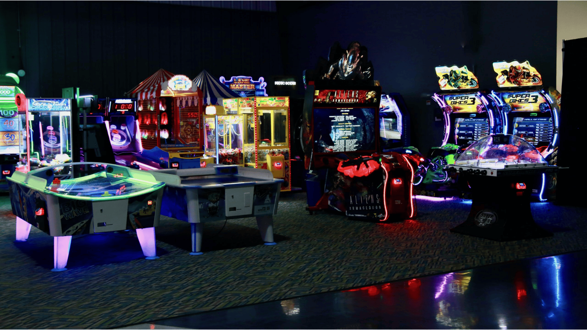 dimly lit arcade with glowing game machines and air hockey tables