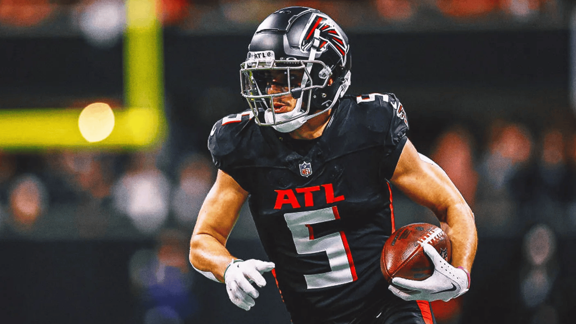 drake london in a black atl jersey and helmet runs with a football focused and determined