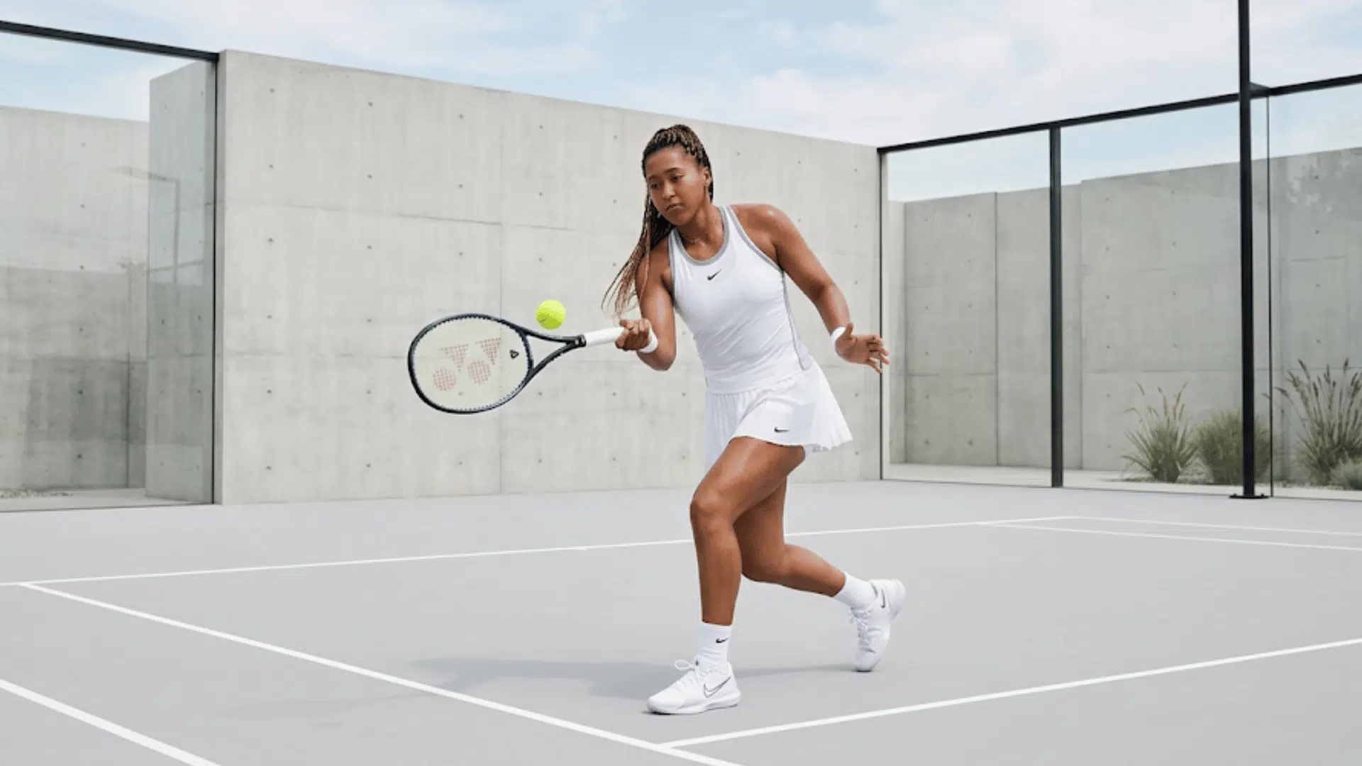female tennis player in white outfit hitting ball on modern cour