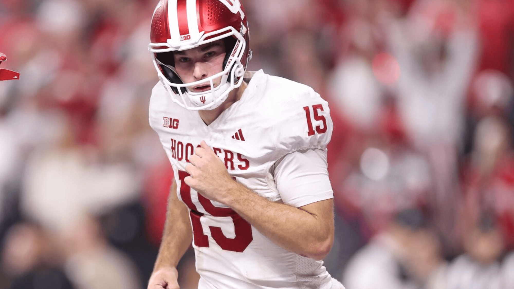 fernando mendoza in a white uniform and red helmet runs on the field with determination