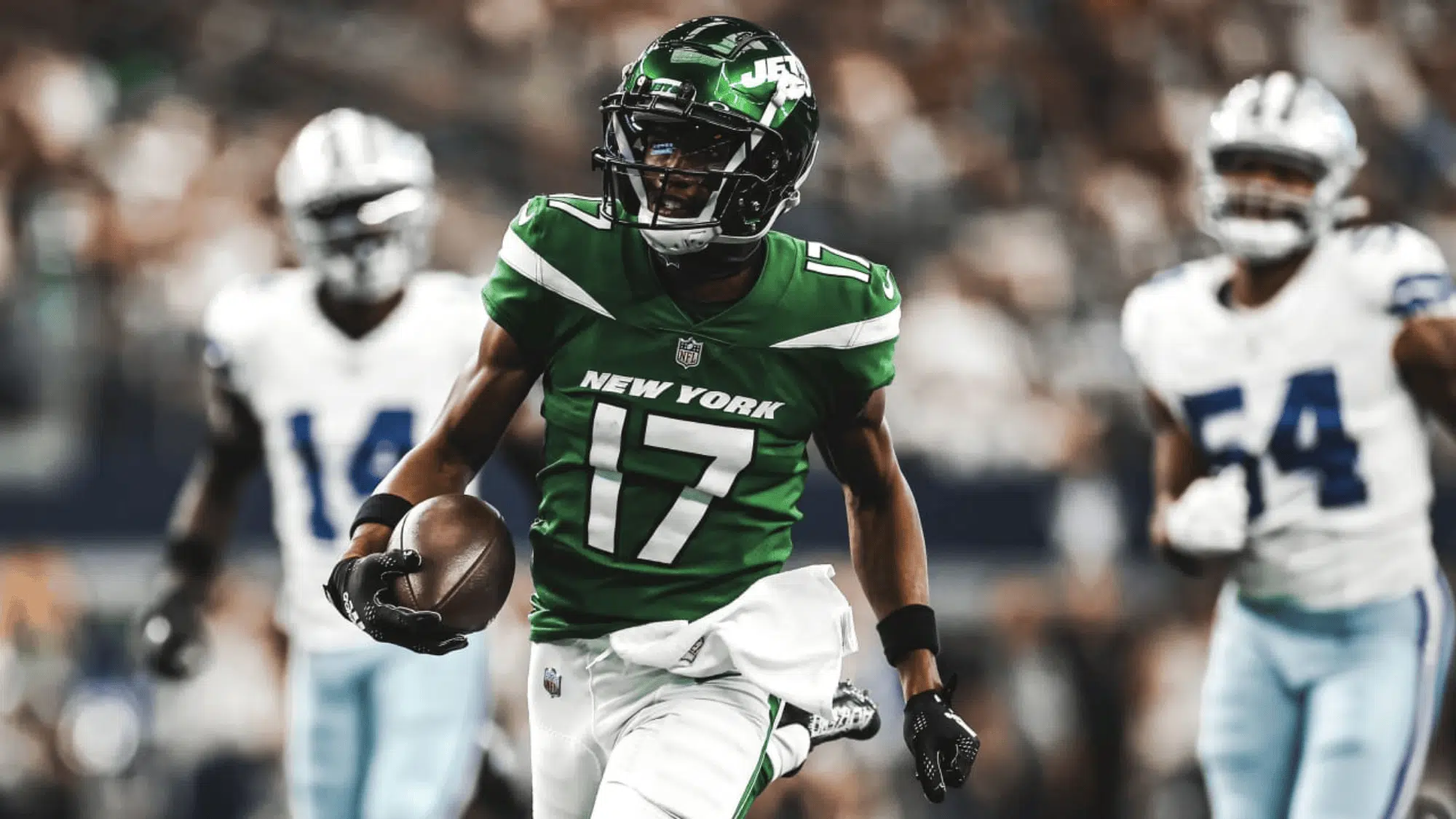 garrett wilson in a green new york jersey runs with the ball pursued by players in white and blue jerseys