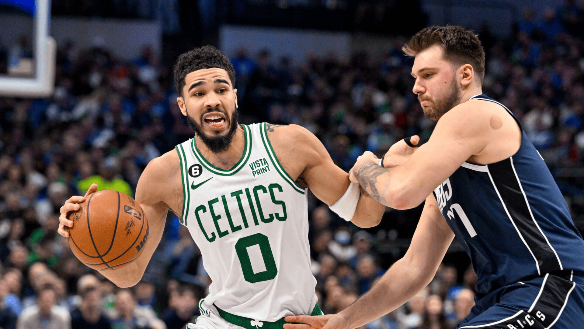 jayson tatum drives past luka doncic during nba game showing matchup between two tall star players on court