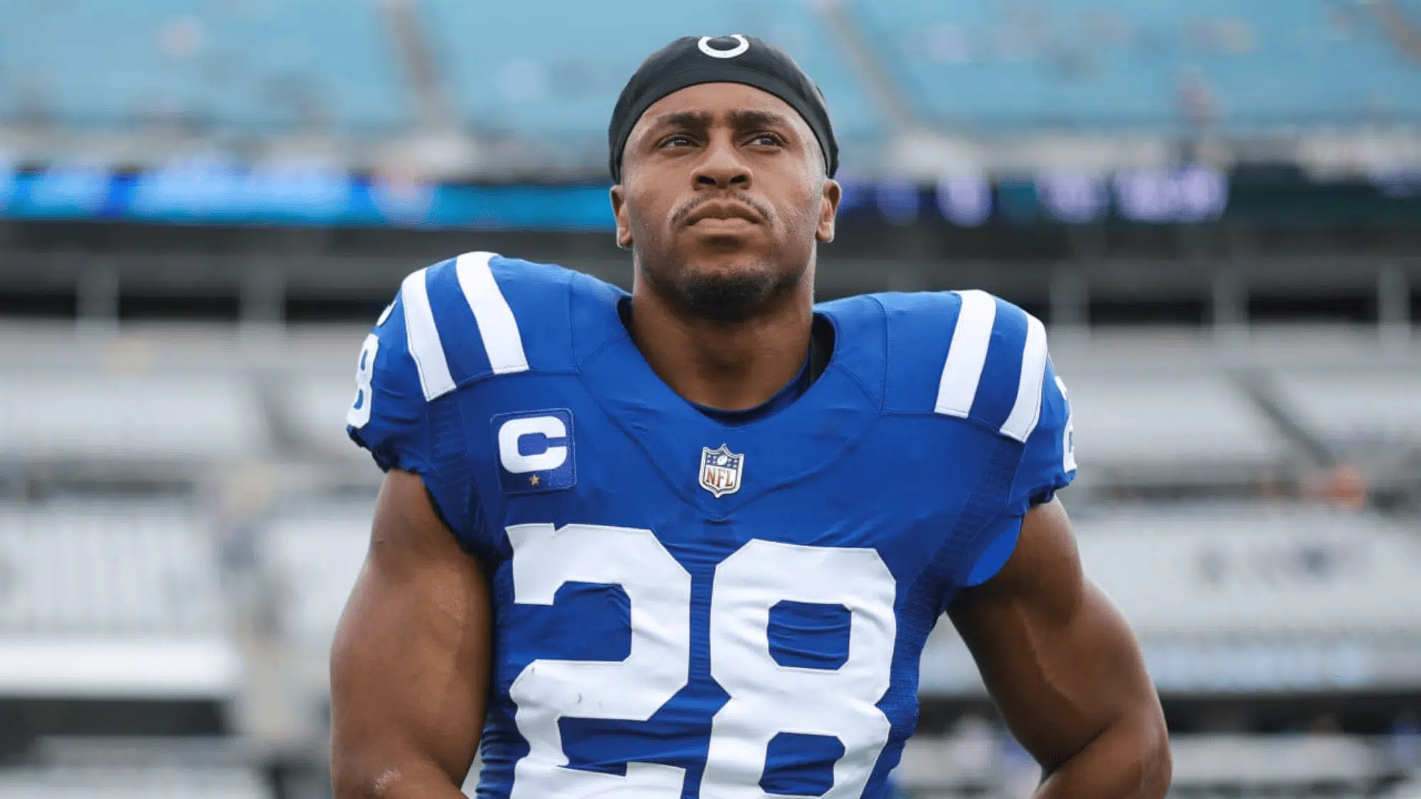 jonathan taylor in a blue and white jersey with number 28 stands confidently on a field